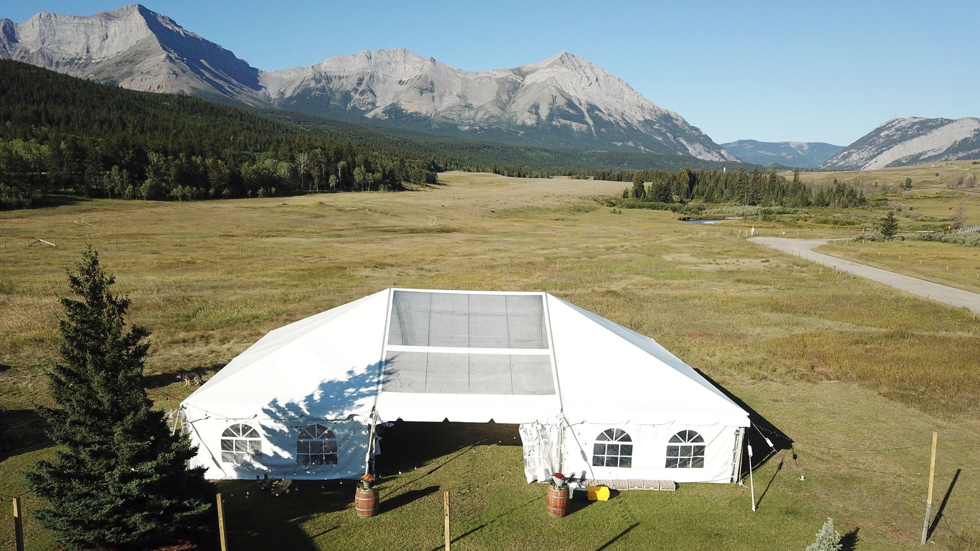 An aerial view of a large white tent in a field with mountains in the background.