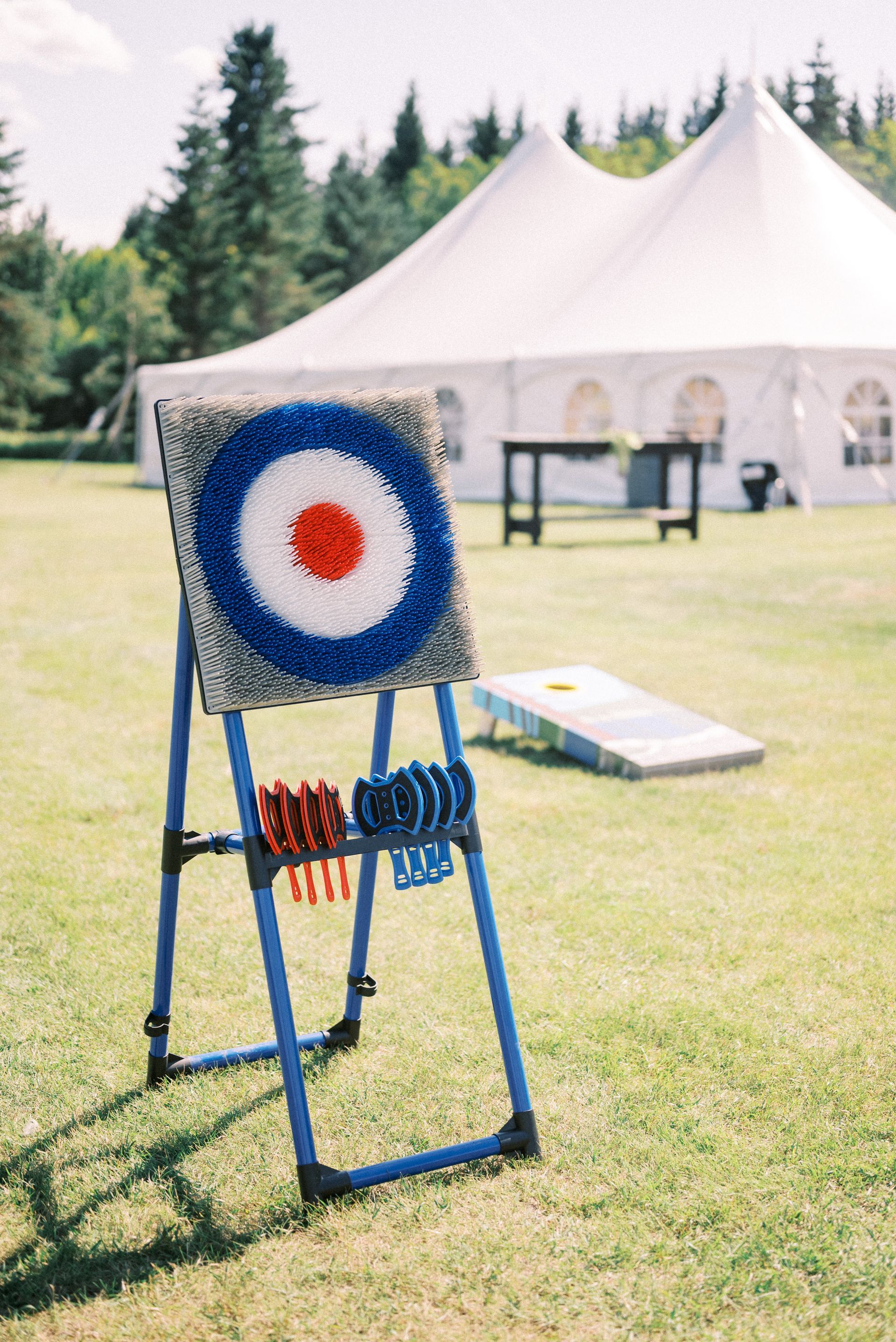 A blue and white target with a red center is sitting in the grass in front of a tent.