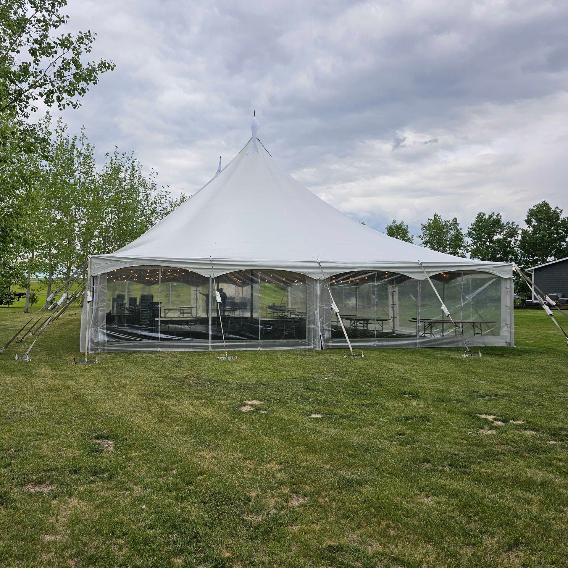 A large white tent is sitting in the middle of a grassy field.