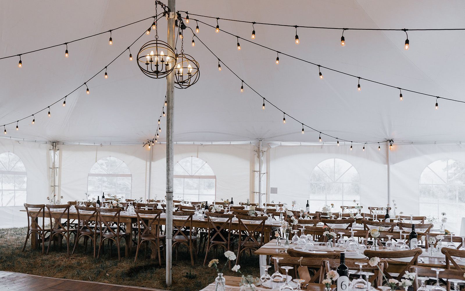 A large tent with tables and chairs set up for a wedding reception.