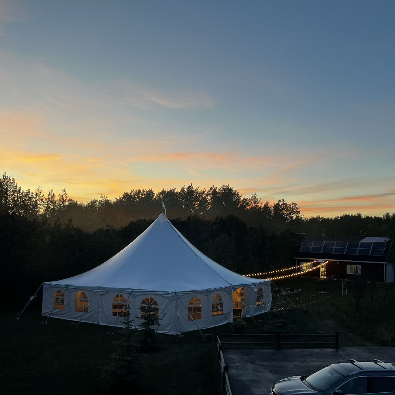 A large white tent with a sunset in the background