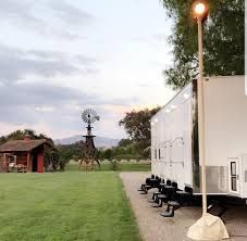 A trailer is parked in a grassy field next to a windmill.