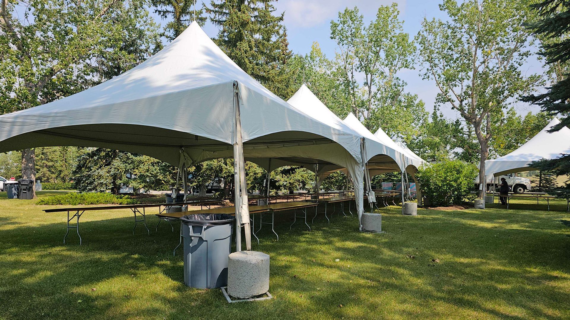 A group of white tents are sitting in a grassy field.