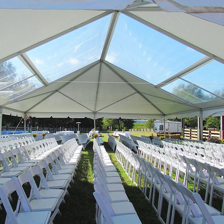 Rows of white chairs under a clear tent