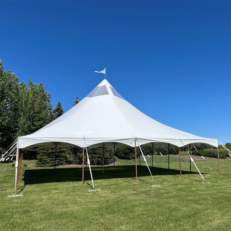 A large white tent is sitting in the middle of a grassy field