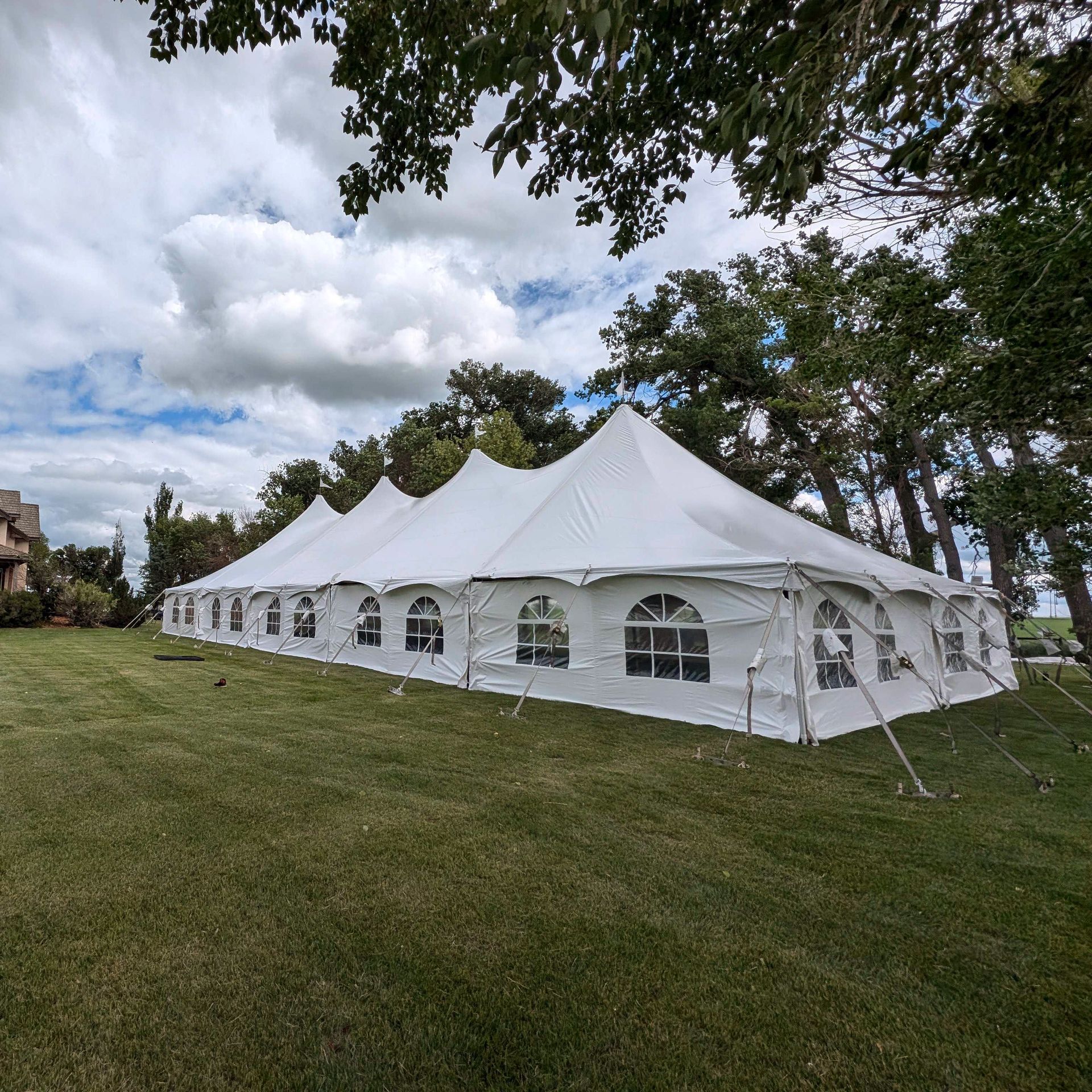 A large white tent is sitting in the middle of a grassy field.
