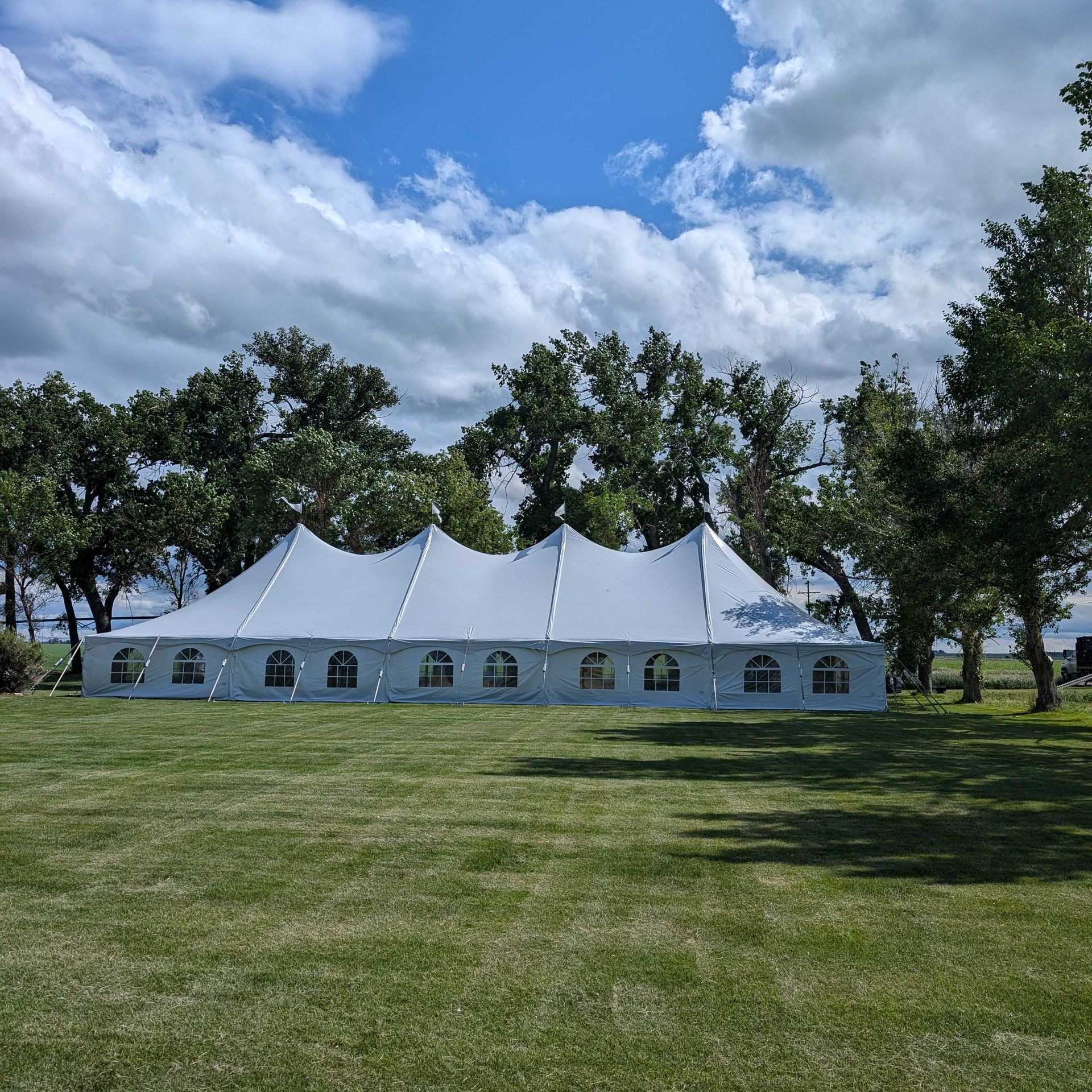 A large white tent is sitting in the middle of a grassy field.