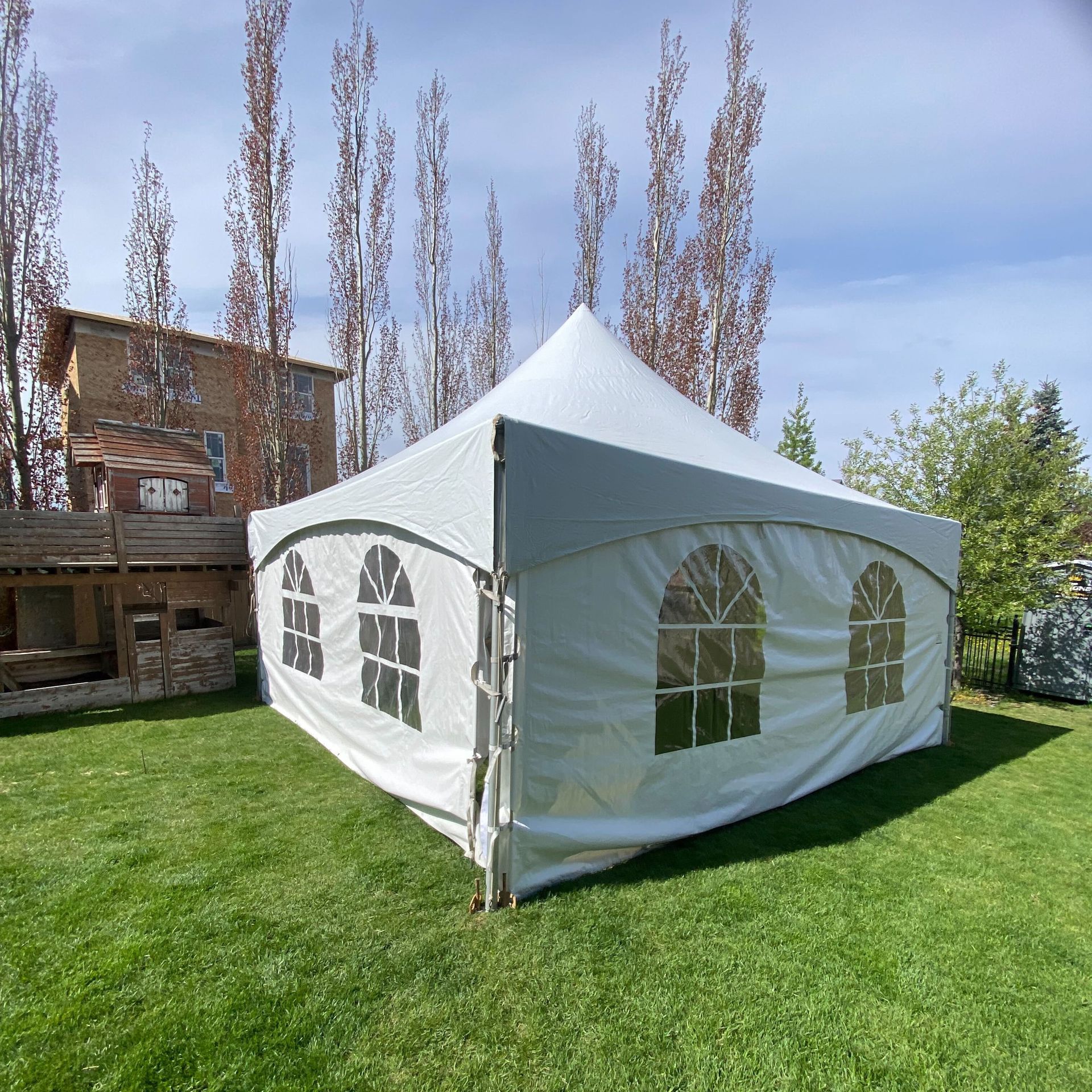 A white tent is sitting in the middle of a lush green field.