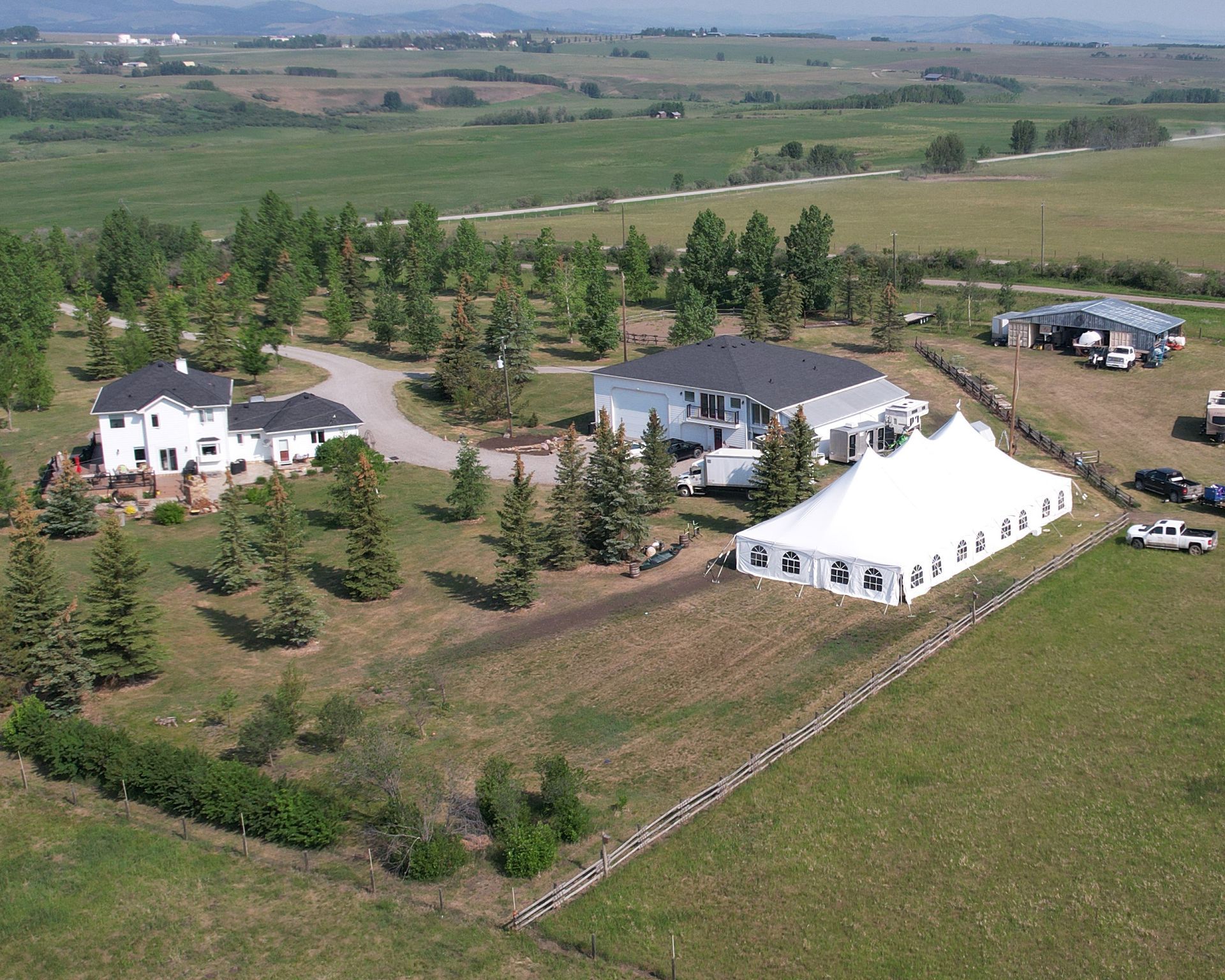 An aerial view of a house and tent in a field