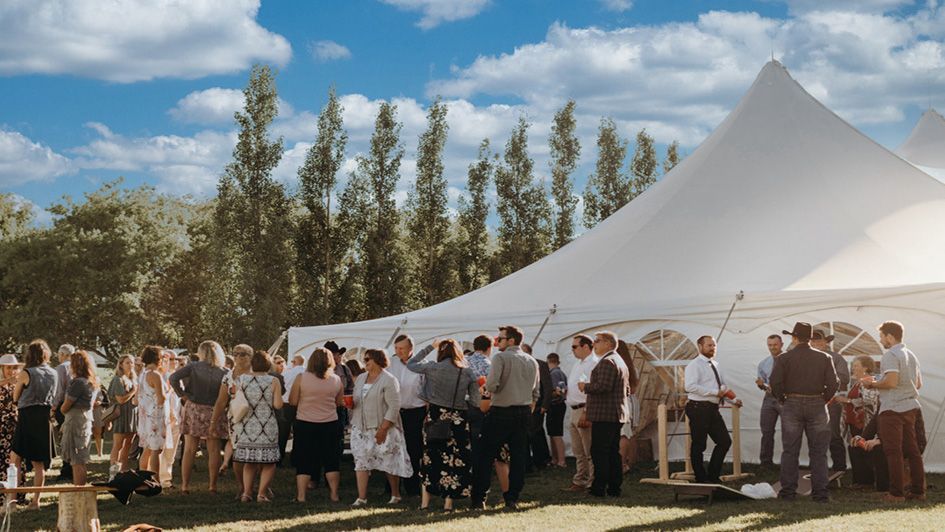 A group of people are standing outside of a white tent.