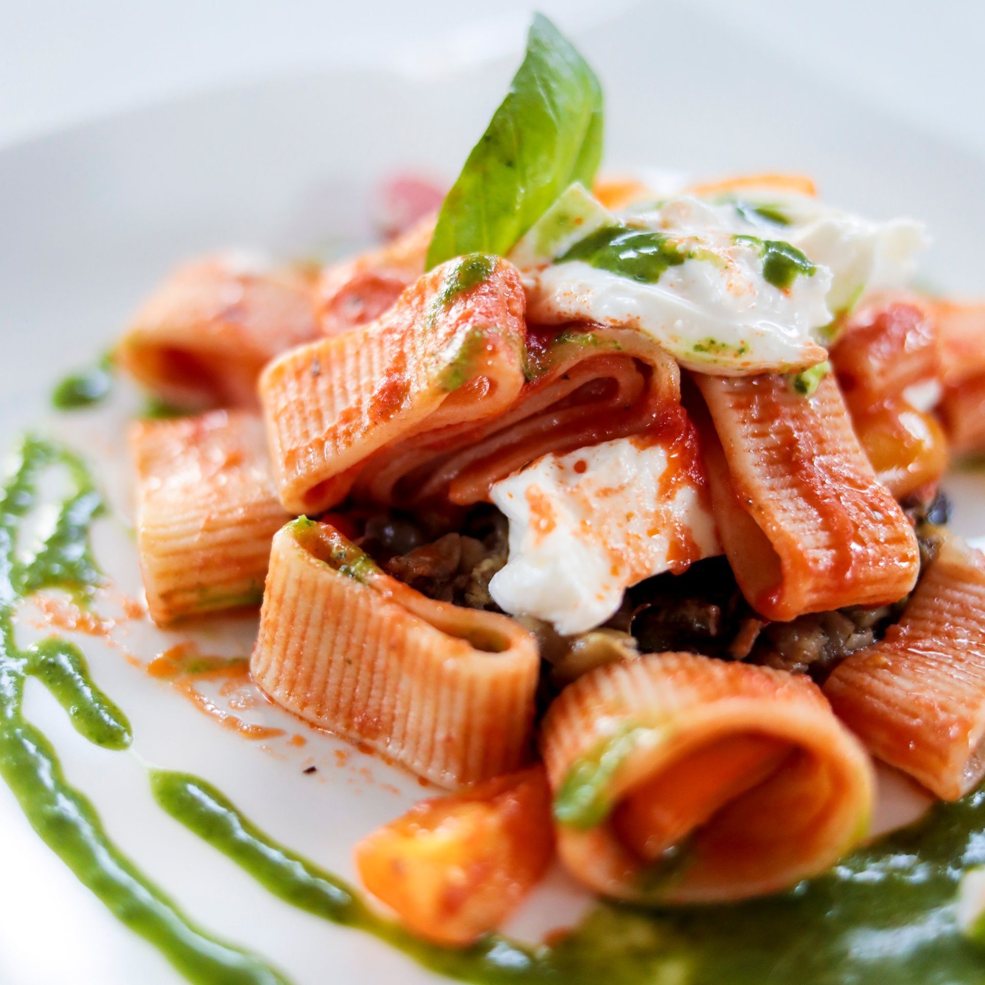 Un primo piano di un piatto di pasta con sugo e salsa verde