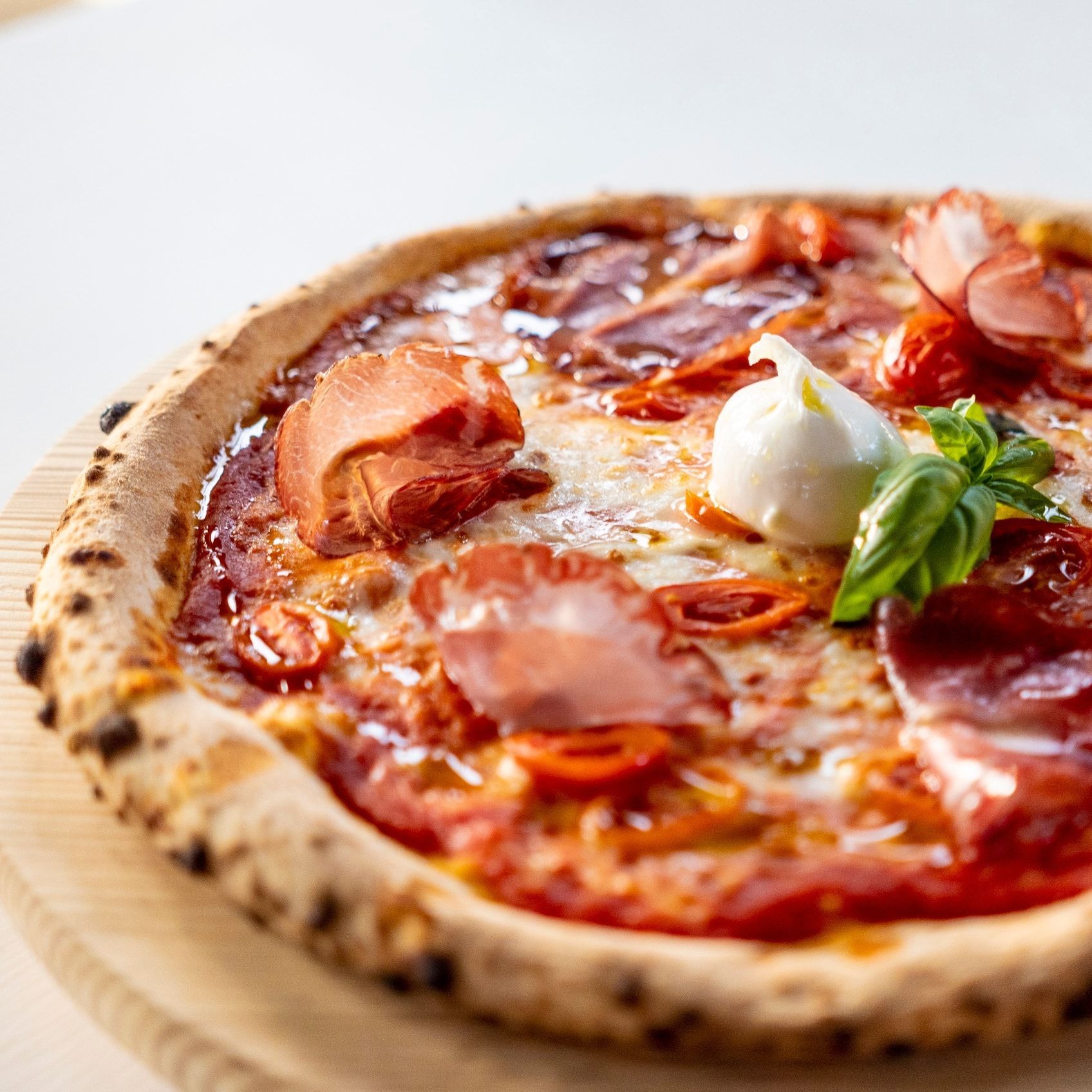 Una pizza è appoggiata su un tagliere di legno su un tavolo.