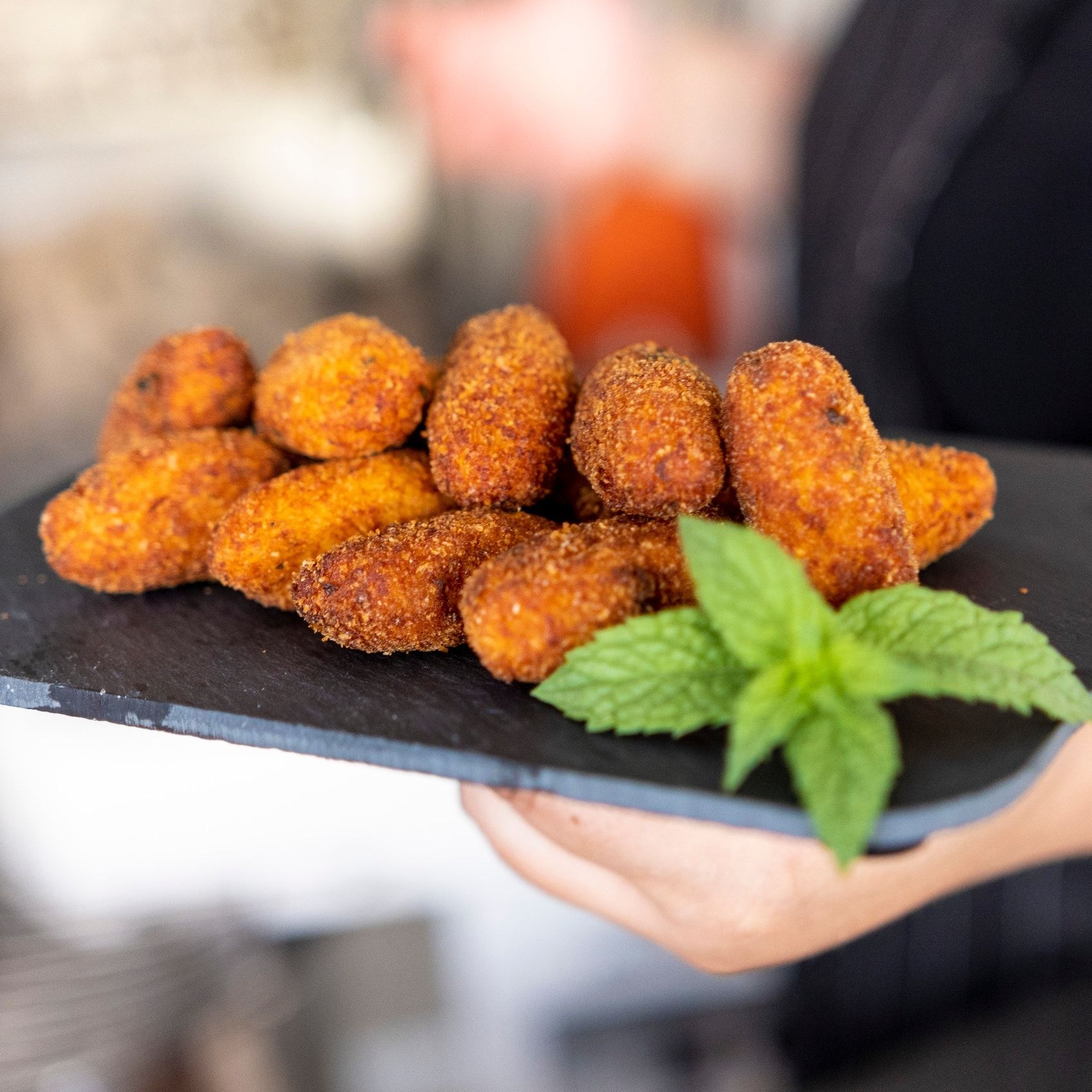 Una persona tiene in mano un vassoio di cibo con sopra delle foglie di menta.
