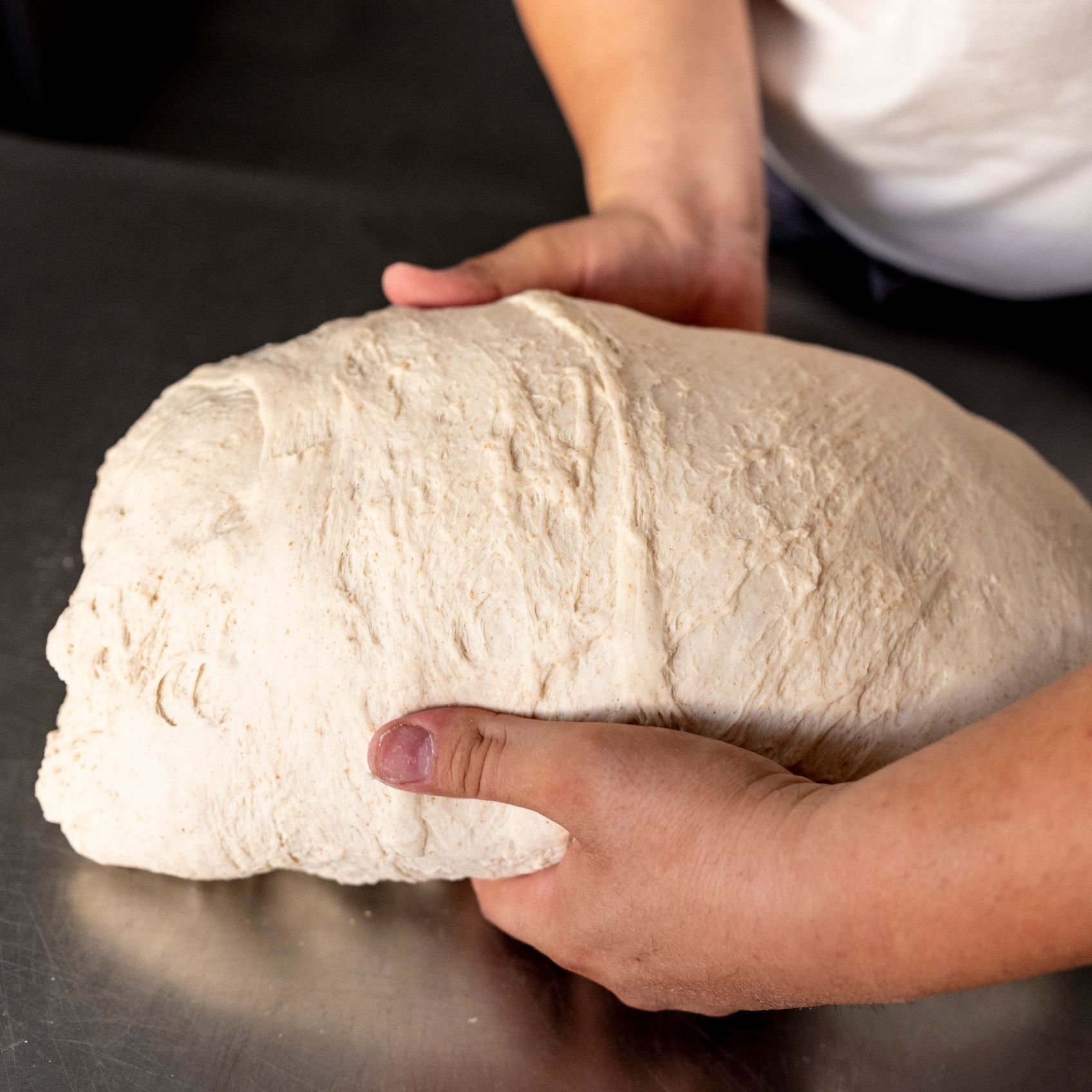 Una persona tiene in mano un grosso pezzo di pasta