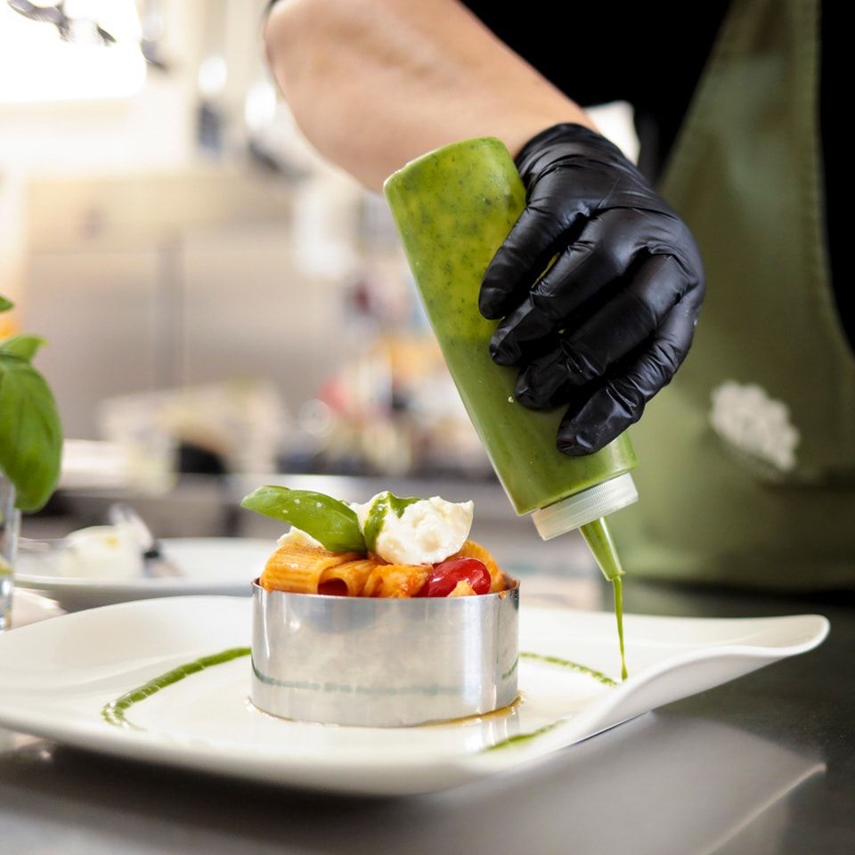 Una persona sta versando la salsa su un piatto di cibo.