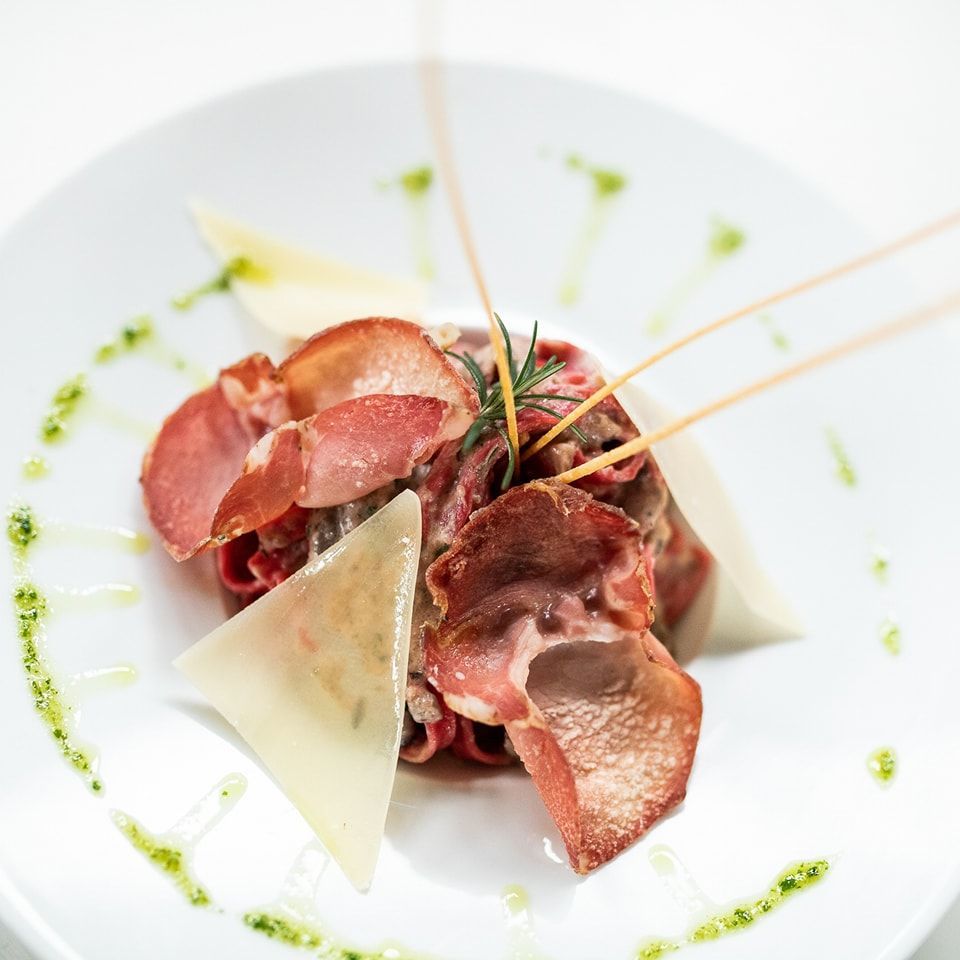 Un piatto bianco con sopra fette di carne e verdure