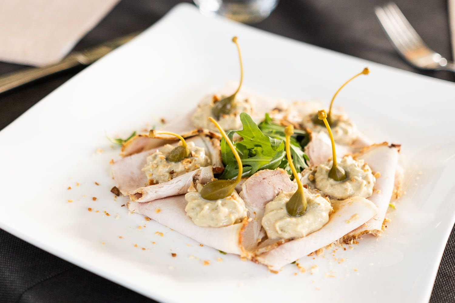 Un piatto bianco con sopra carne e verdure su un tavolo.