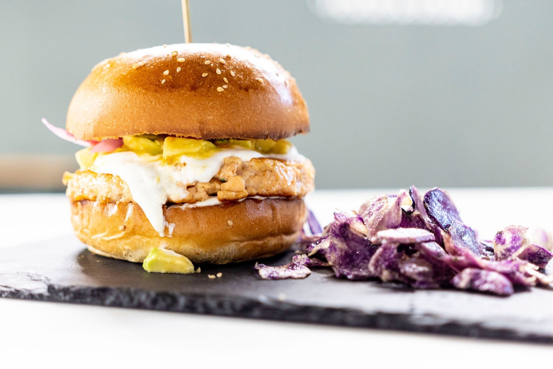 Un hamburger è appoggiato su un tagliere accanto a una pila di insalata di cavolo.