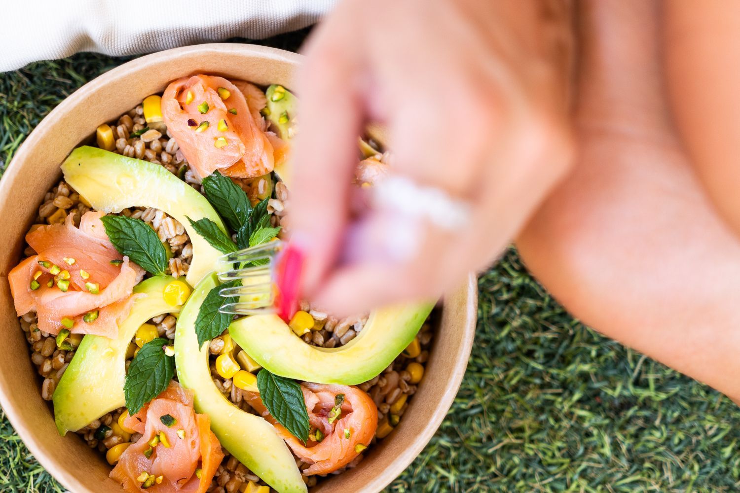 Una donna mangia un'insalata con una forchetta da una ciotola.
