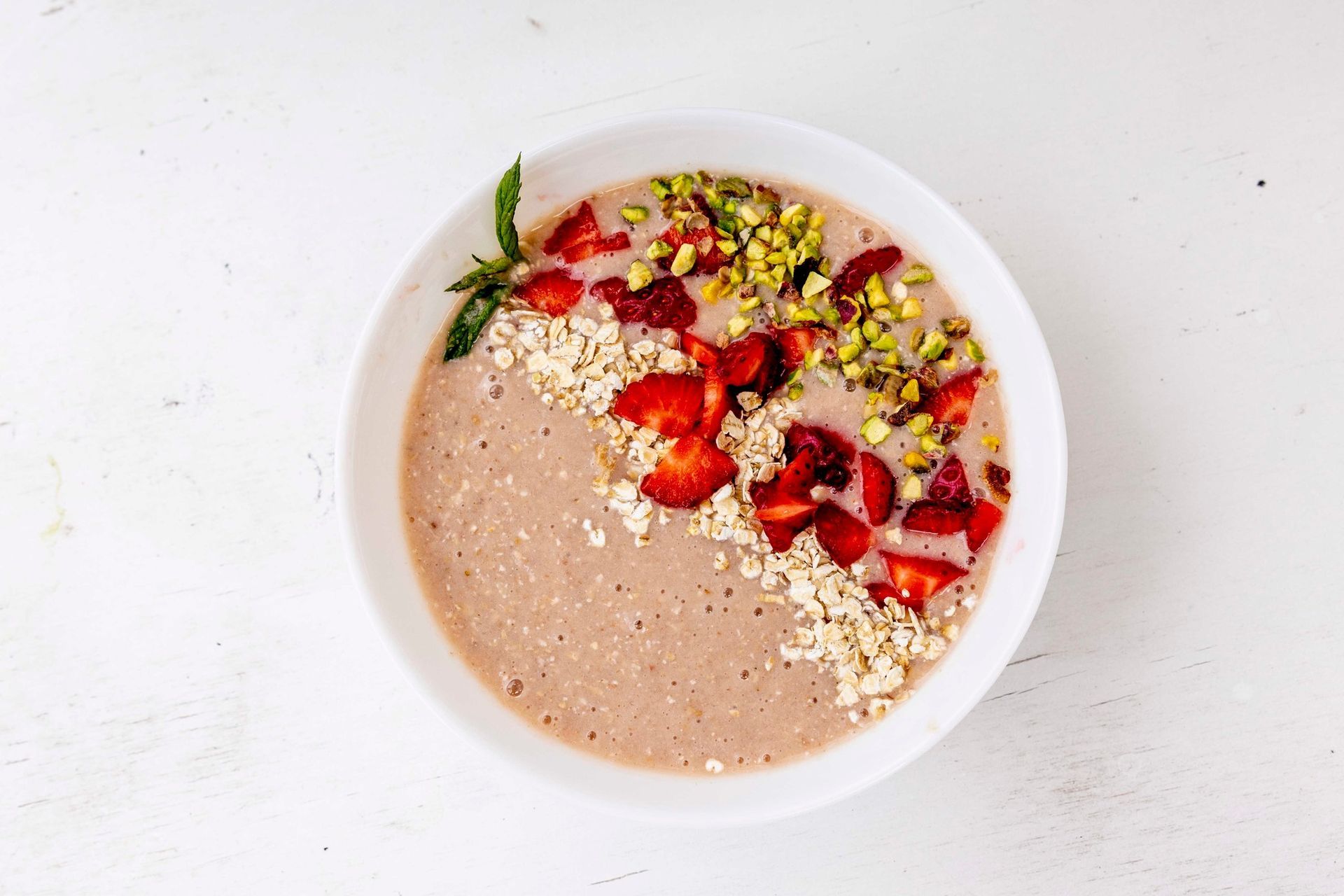 Una ciotola di fiocchi d'avena con fragole e pistacchi sopra.