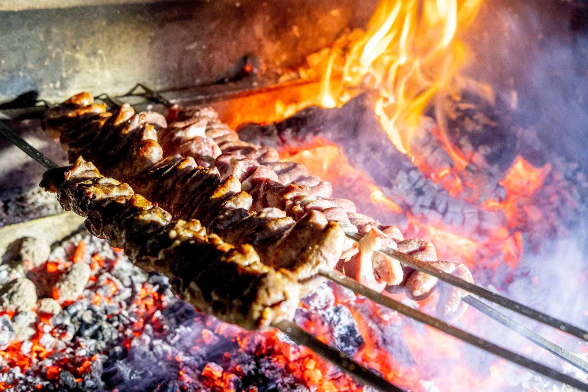 La carne viene cotta su spiedini sul fuoco.