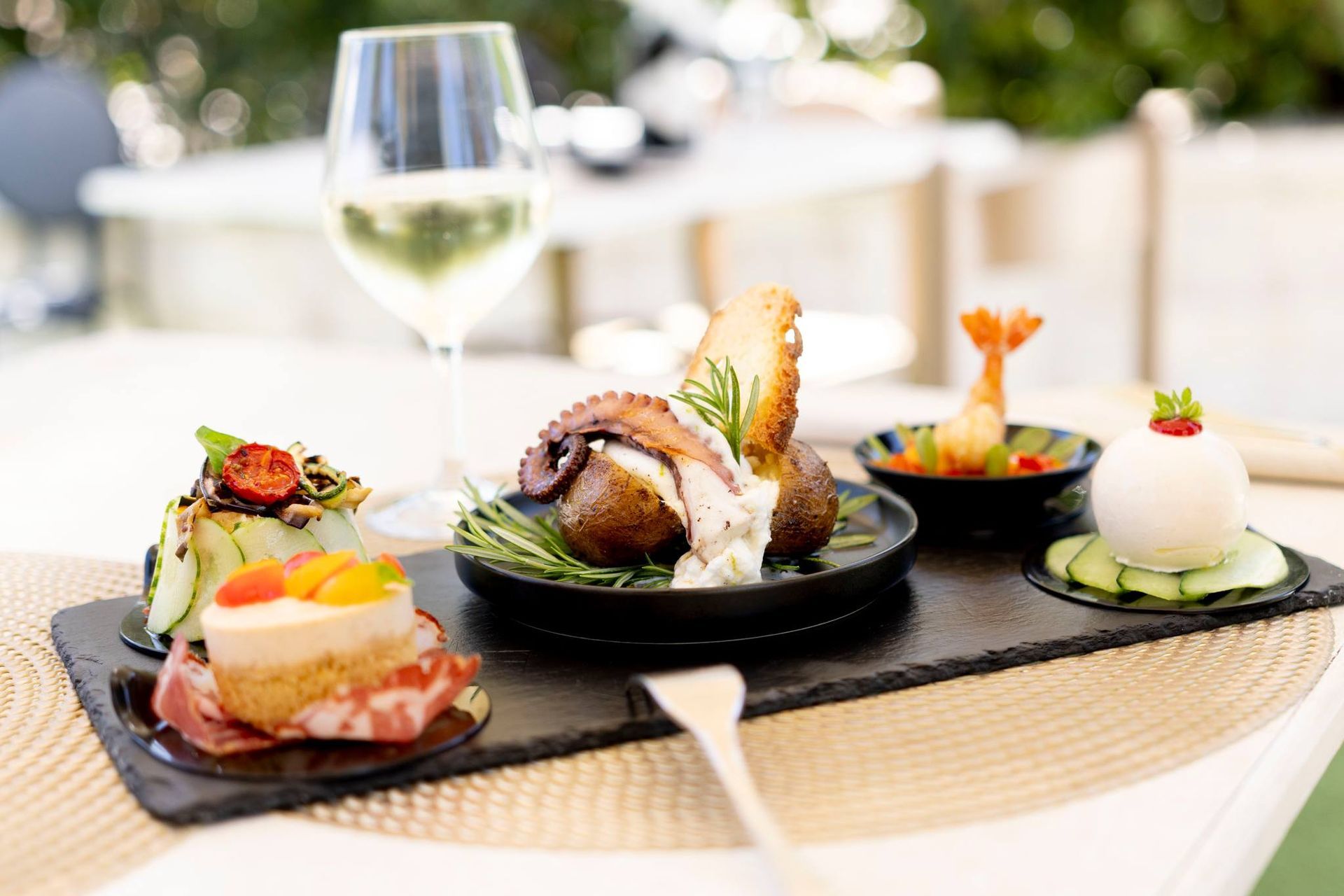 Un vassoio di cibo e un bicchiere di vino su un tavolo.