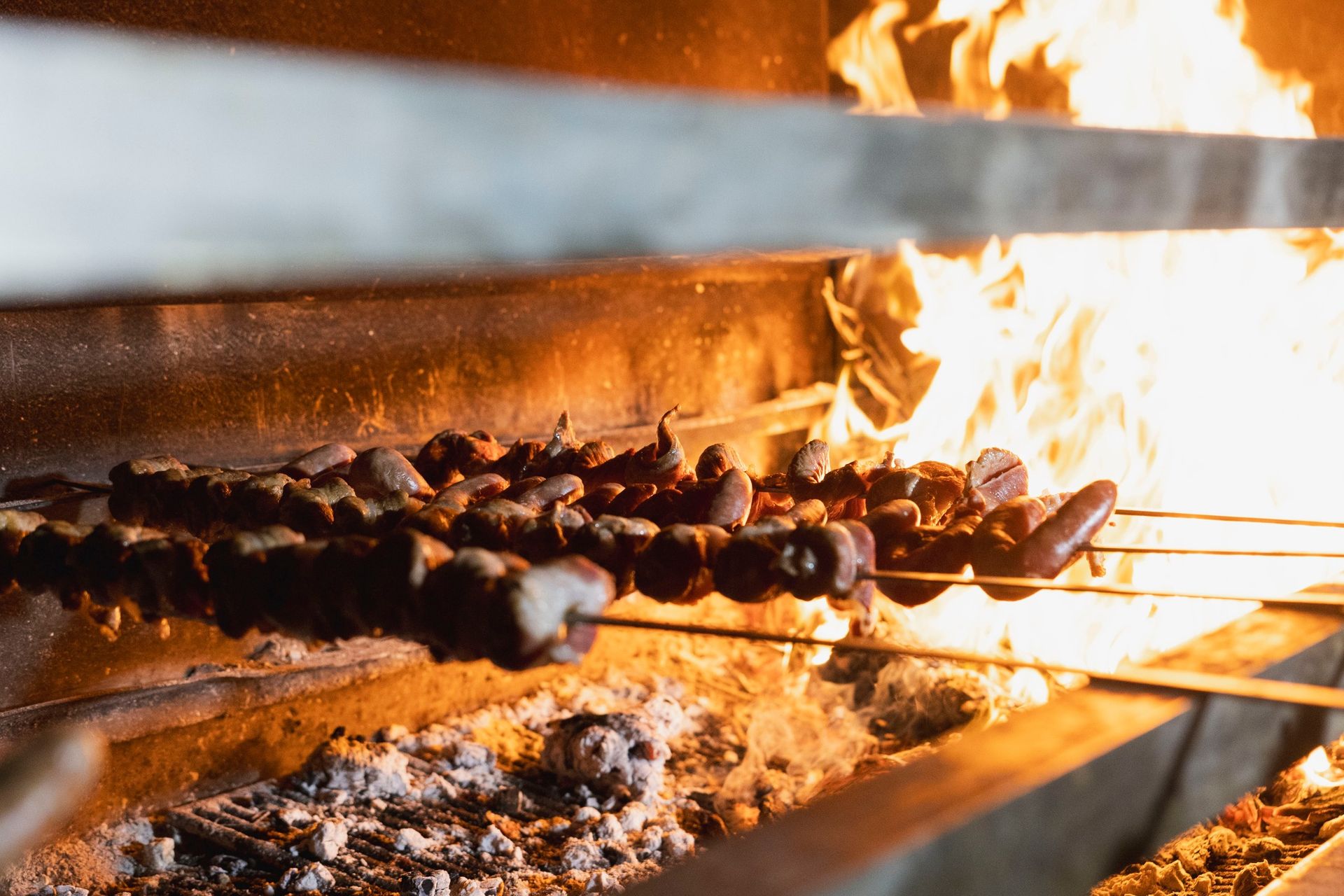 Un mucchio di cibo sta cuocendo su una griglia davanti al fuoco.