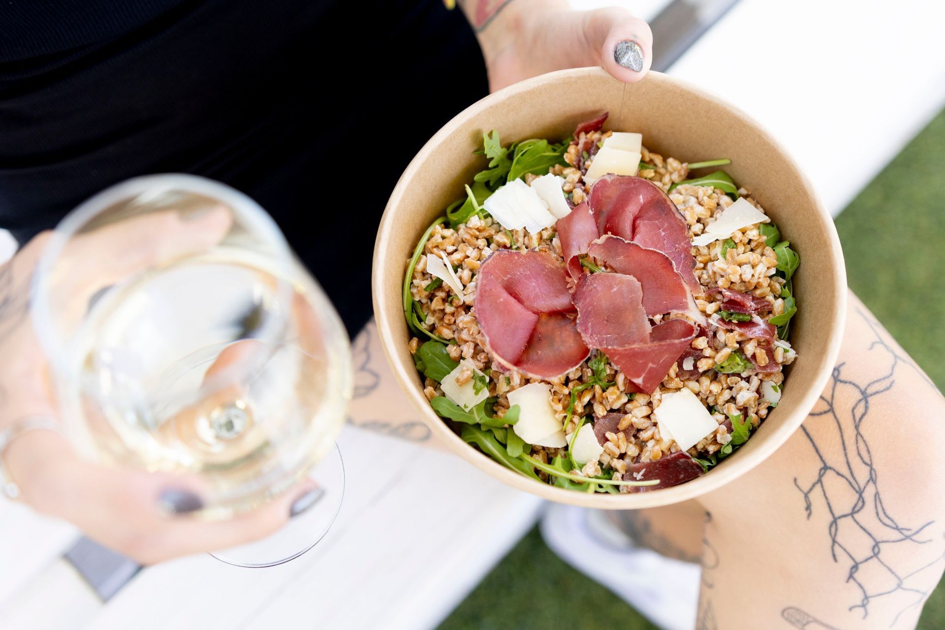 Una persona tiene in mano una ciotola di cibo e un bicchiere di vino.