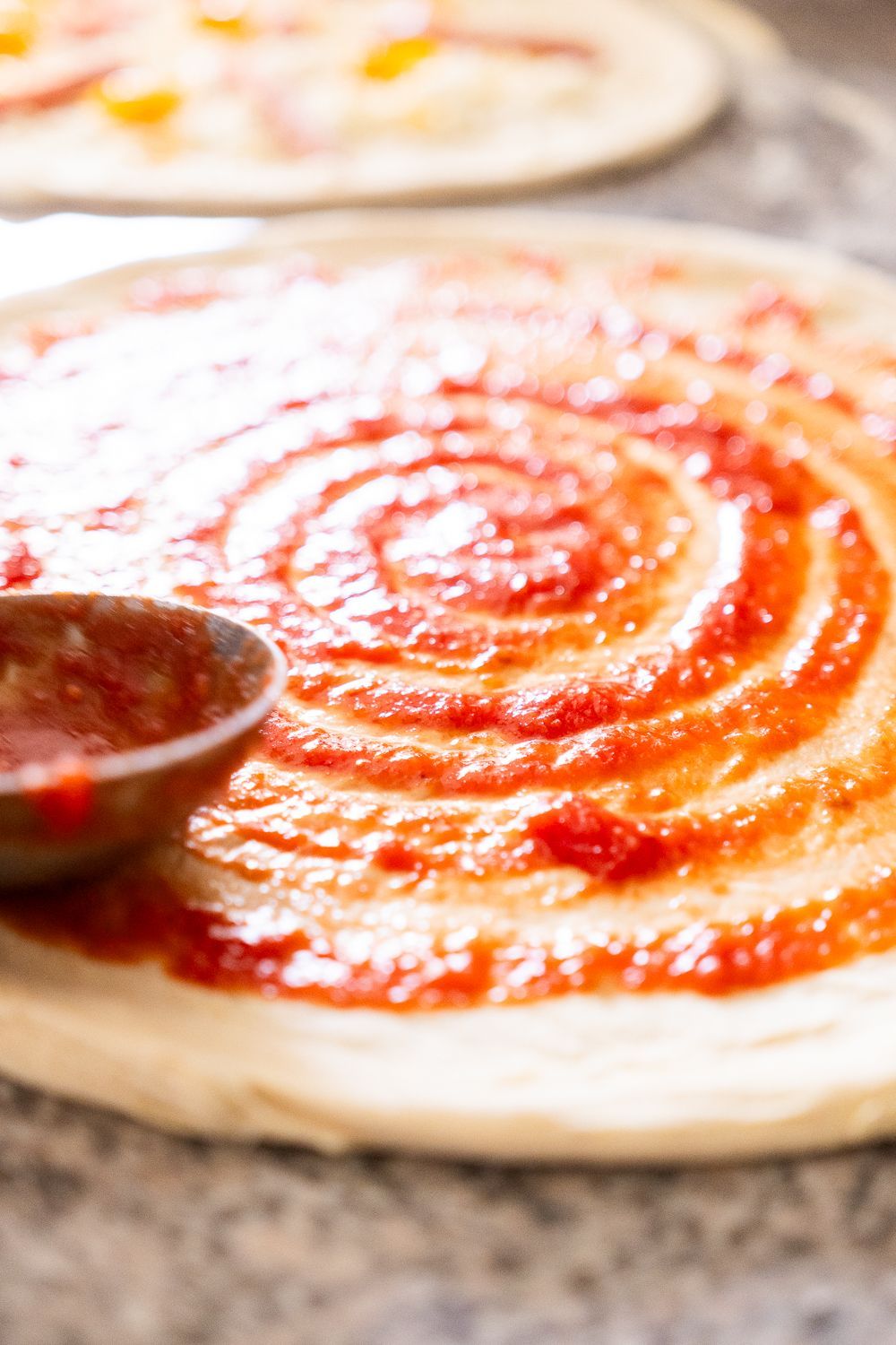 Una pizza con sopra spalmata la salsa di pomodoro.