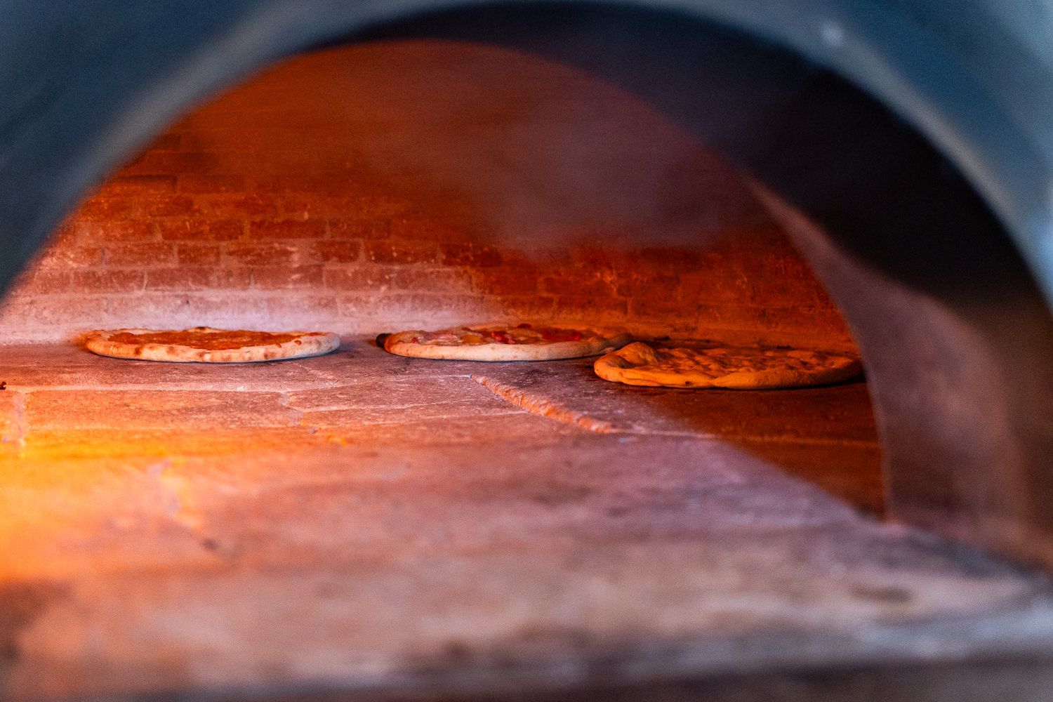 Tre pizze vengono cotte in un forno a legna.
