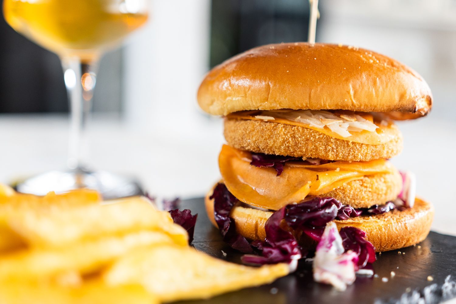 Un hamburger è appoggiato su un tavolo accanto a un bicchiere di birra.