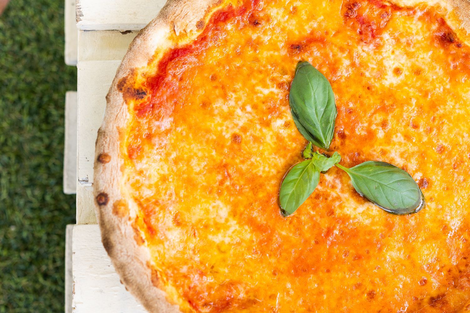 Una pizza con salsa di pomodoro e formaggio è appoggiata su un tavolo di legno.