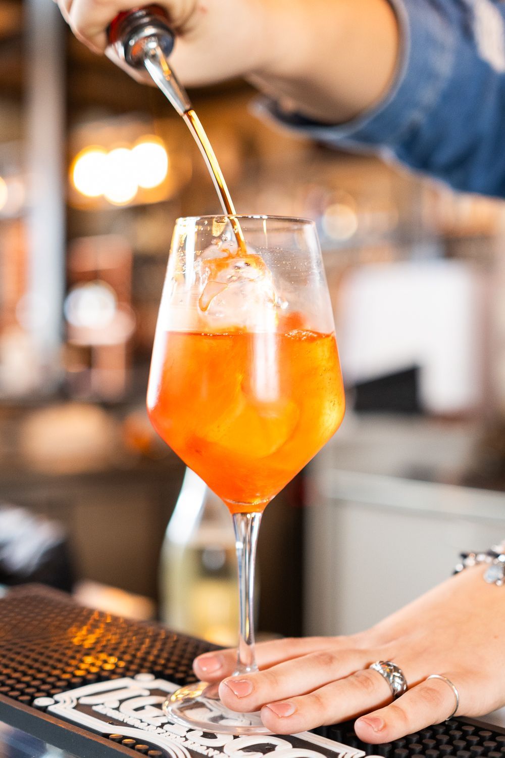 Un barista versa un drink in un bicchiere con ghiaccio.