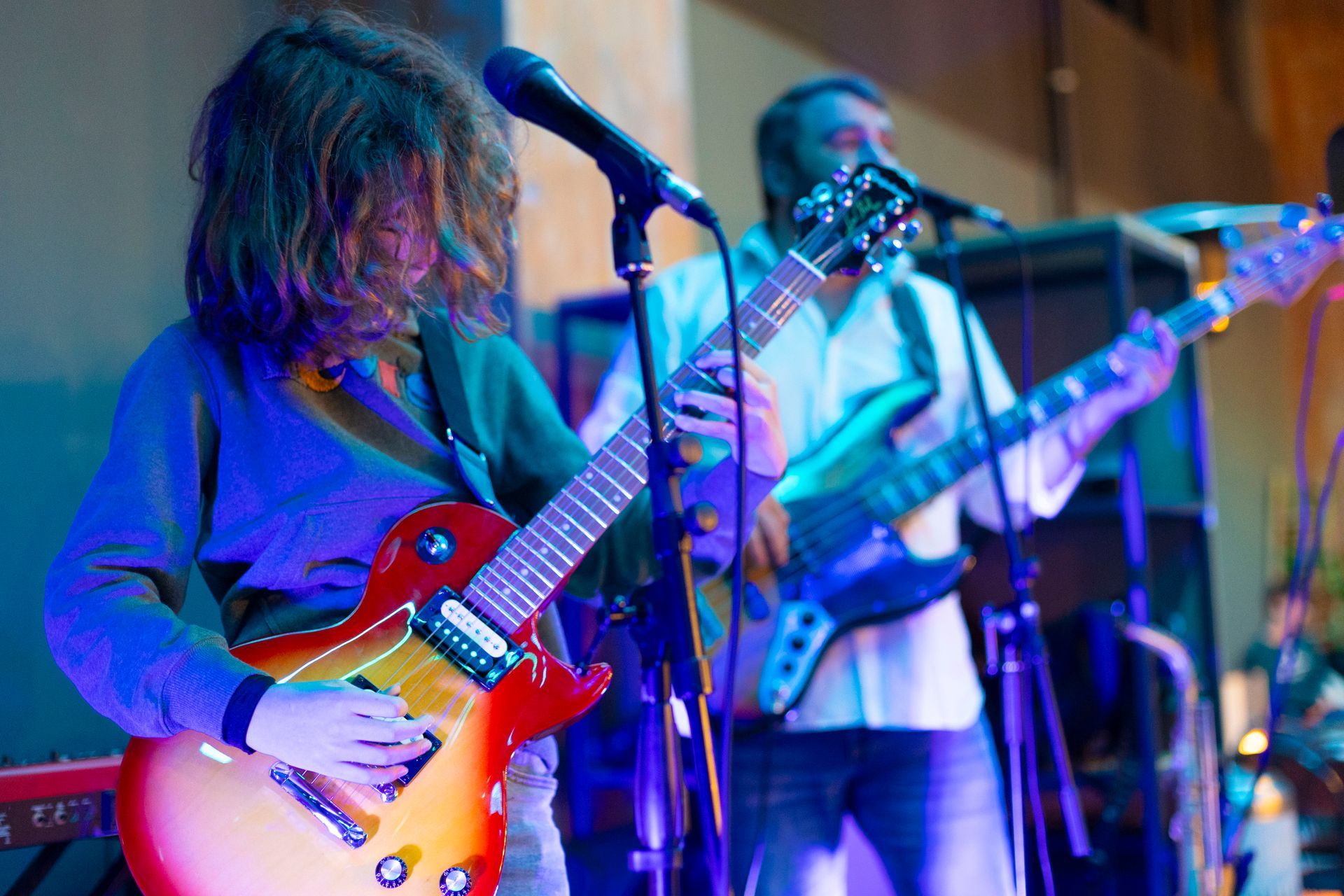 Due uomini suonano la chitarra e cantano nei microfoni su un palco.