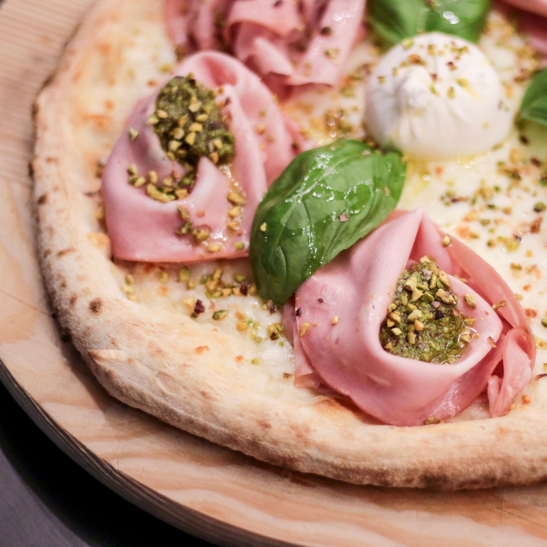 Una pizza con molti condimenti è su un tagliere di legno.