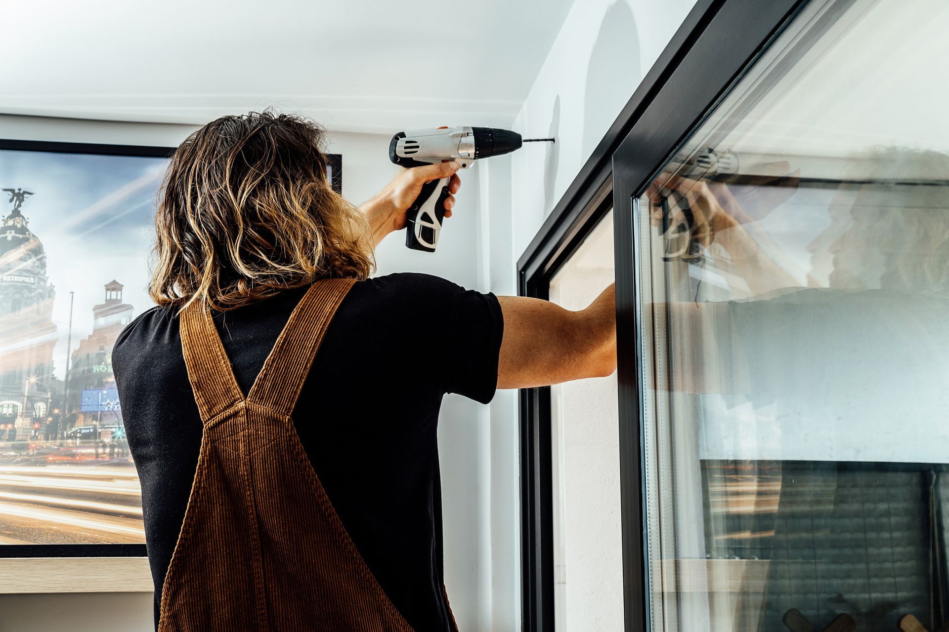 A man is using a drill to install a window.