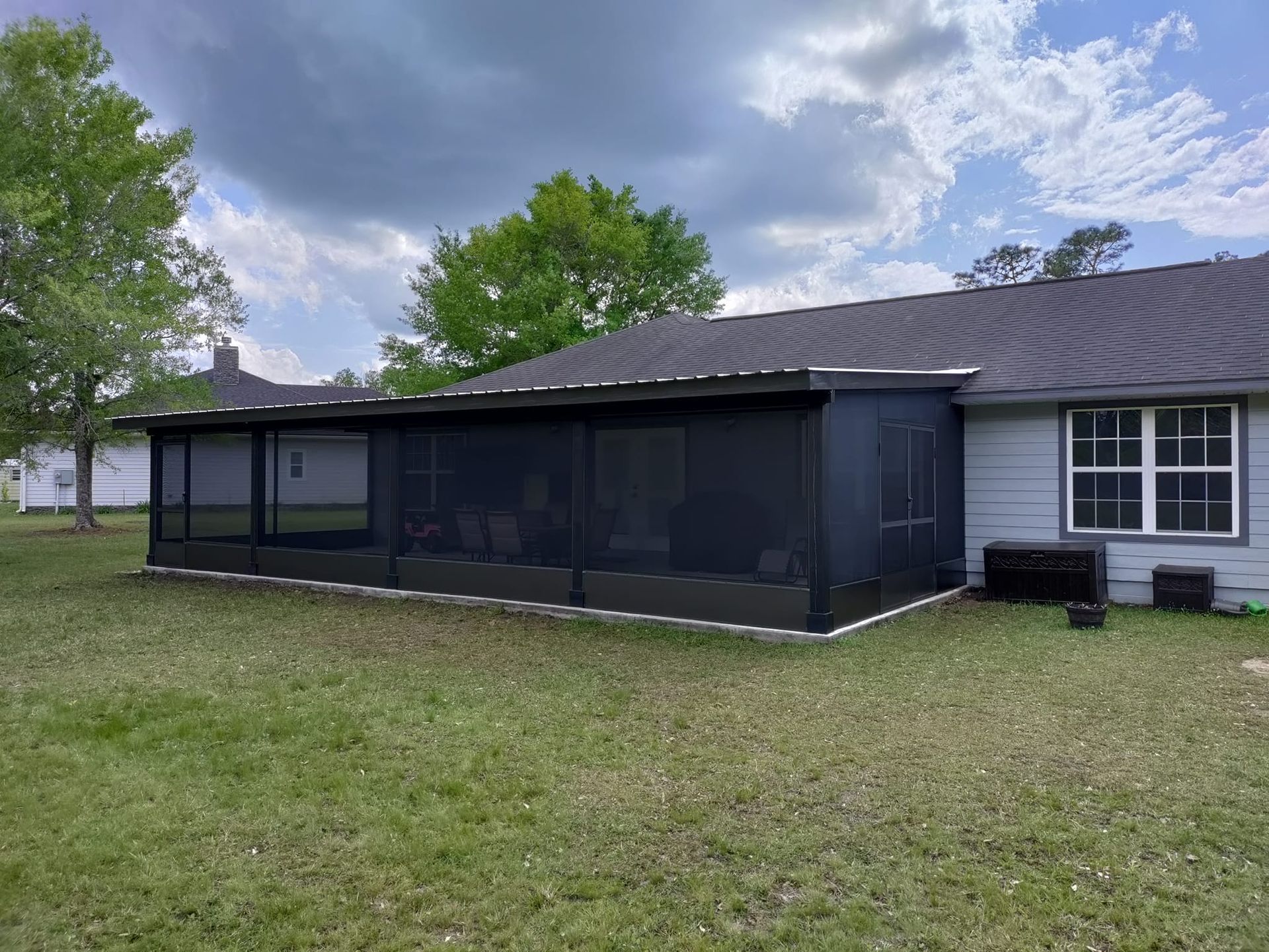There is a screened in porch in the backyard of a house.
