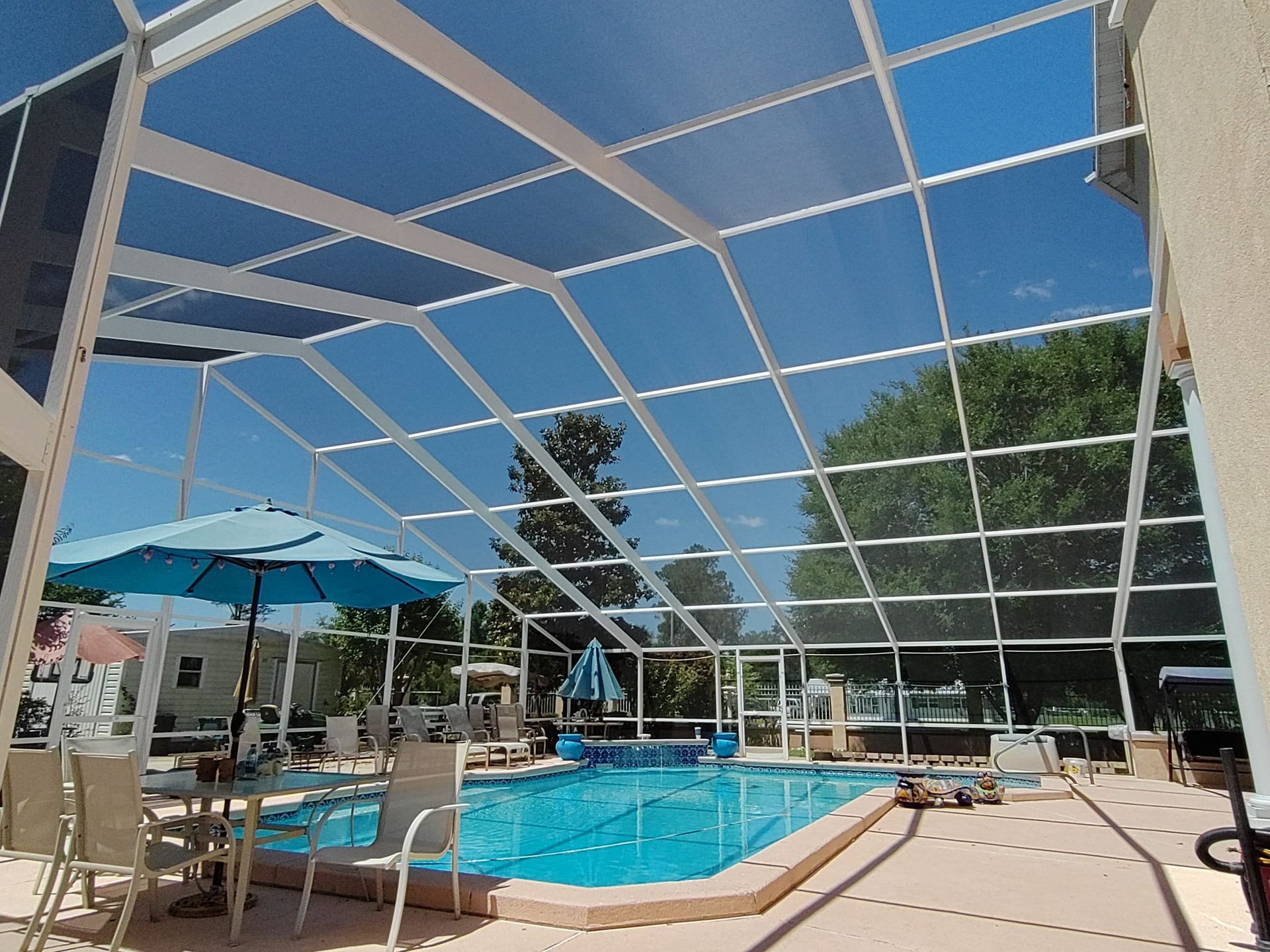 A screened in swimming pool with chairs and umbrellas