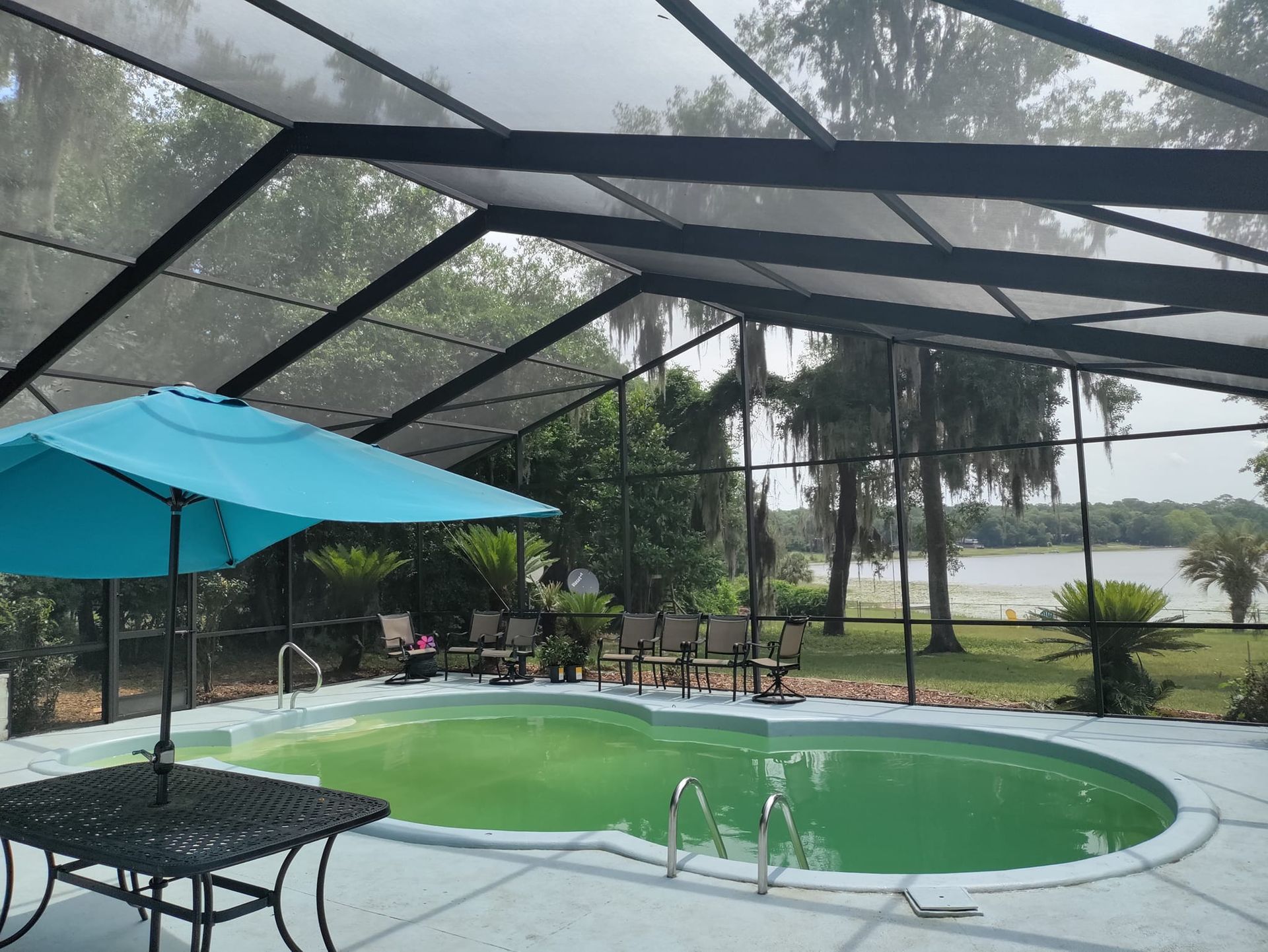 A swimming pool with a blue umbrella and a table