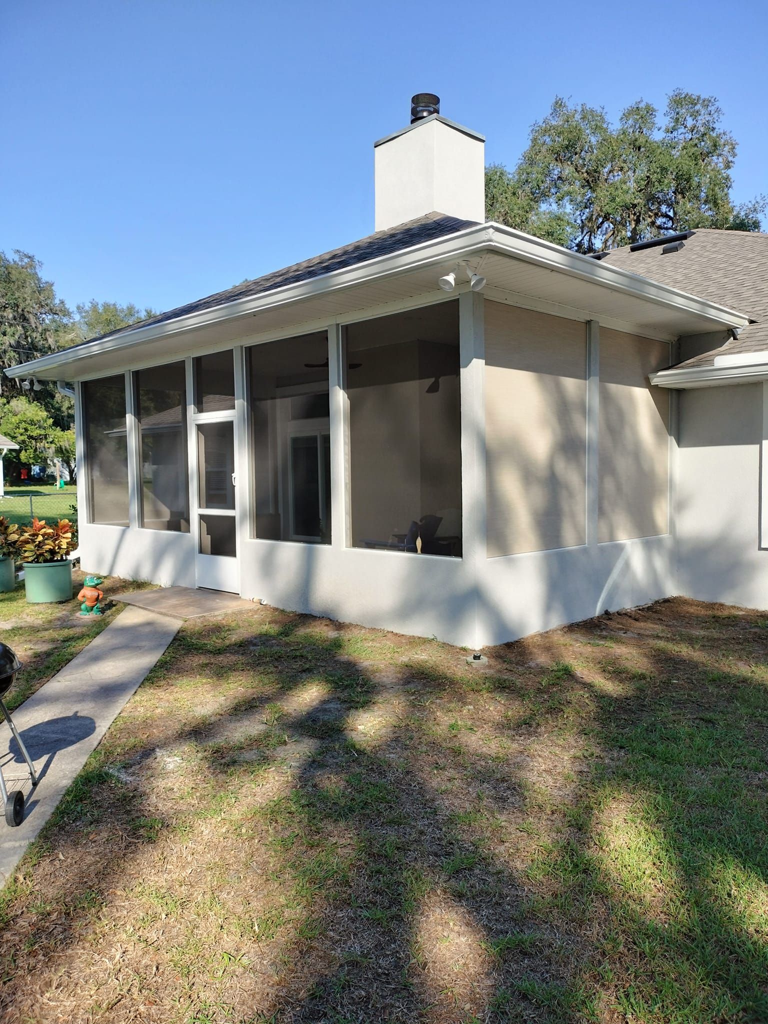 A house with a screened in porch and a walkway leading to it.