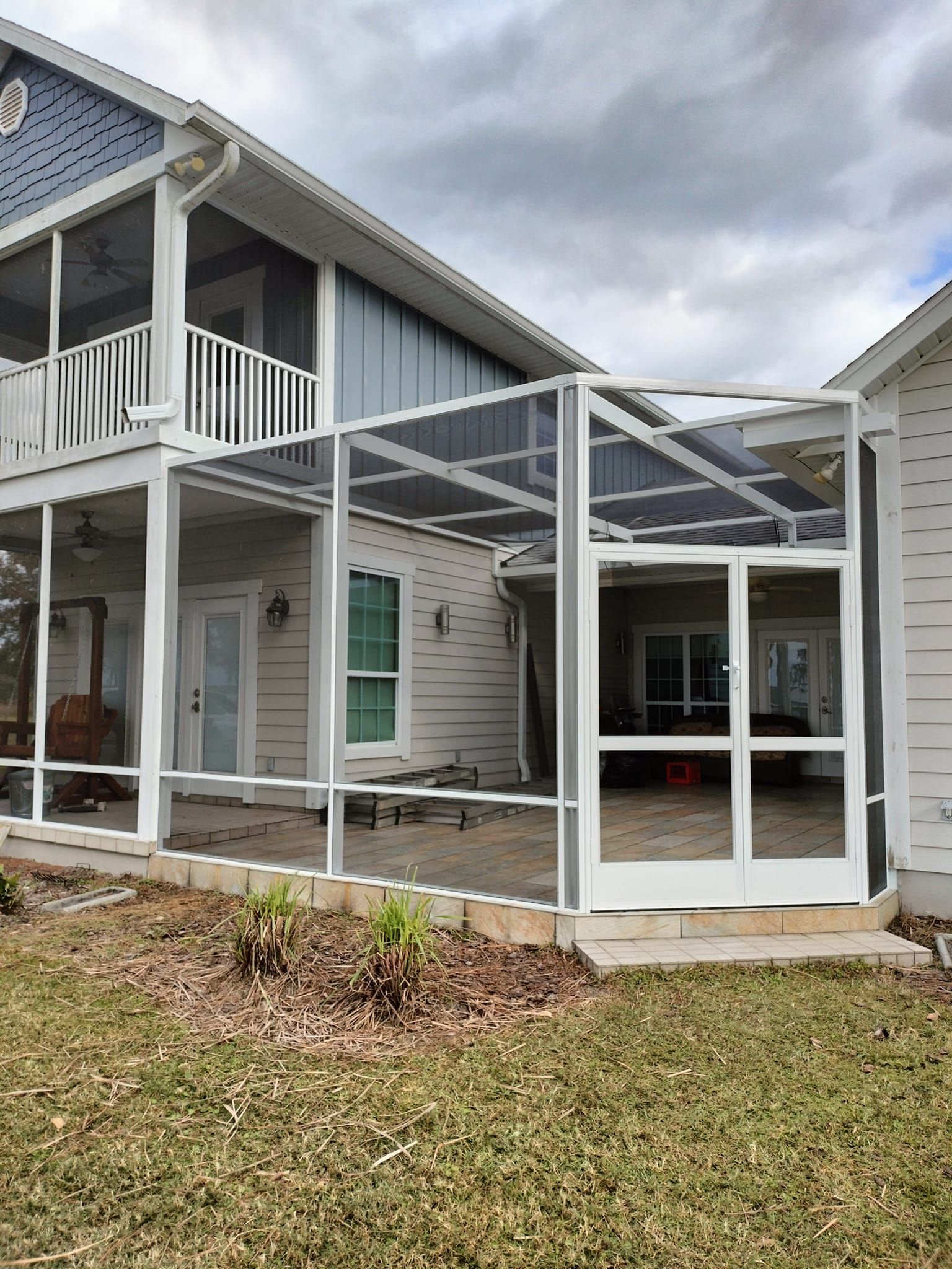 A house with a screened in porch and sliding glass doors.