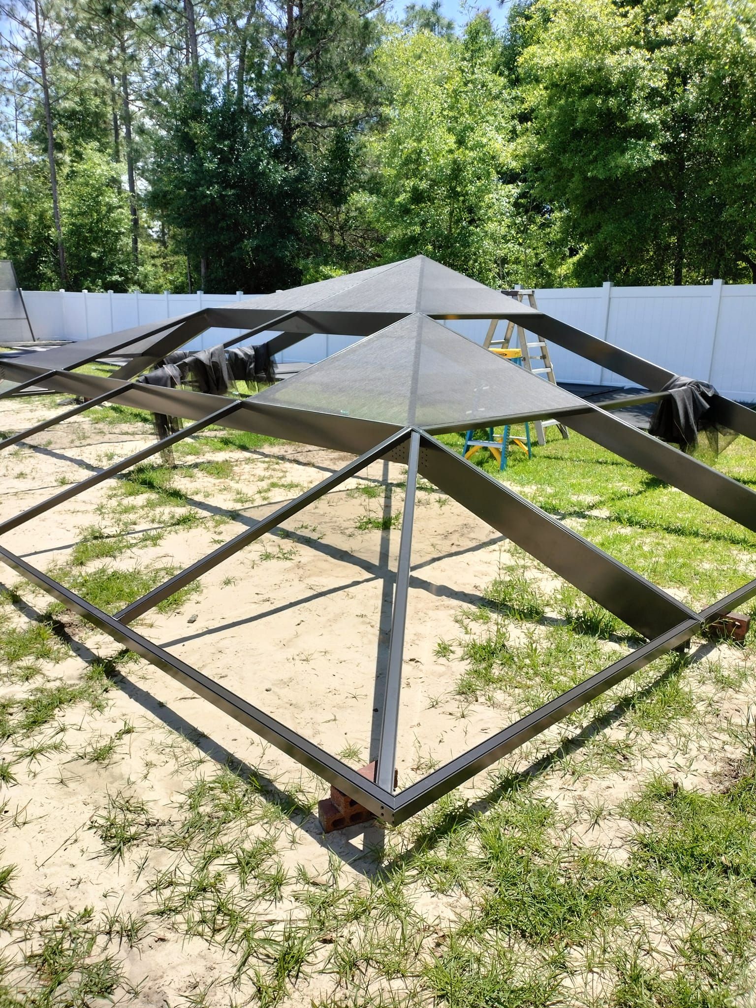 A metal structure is sitting in the middle of a grassy field.