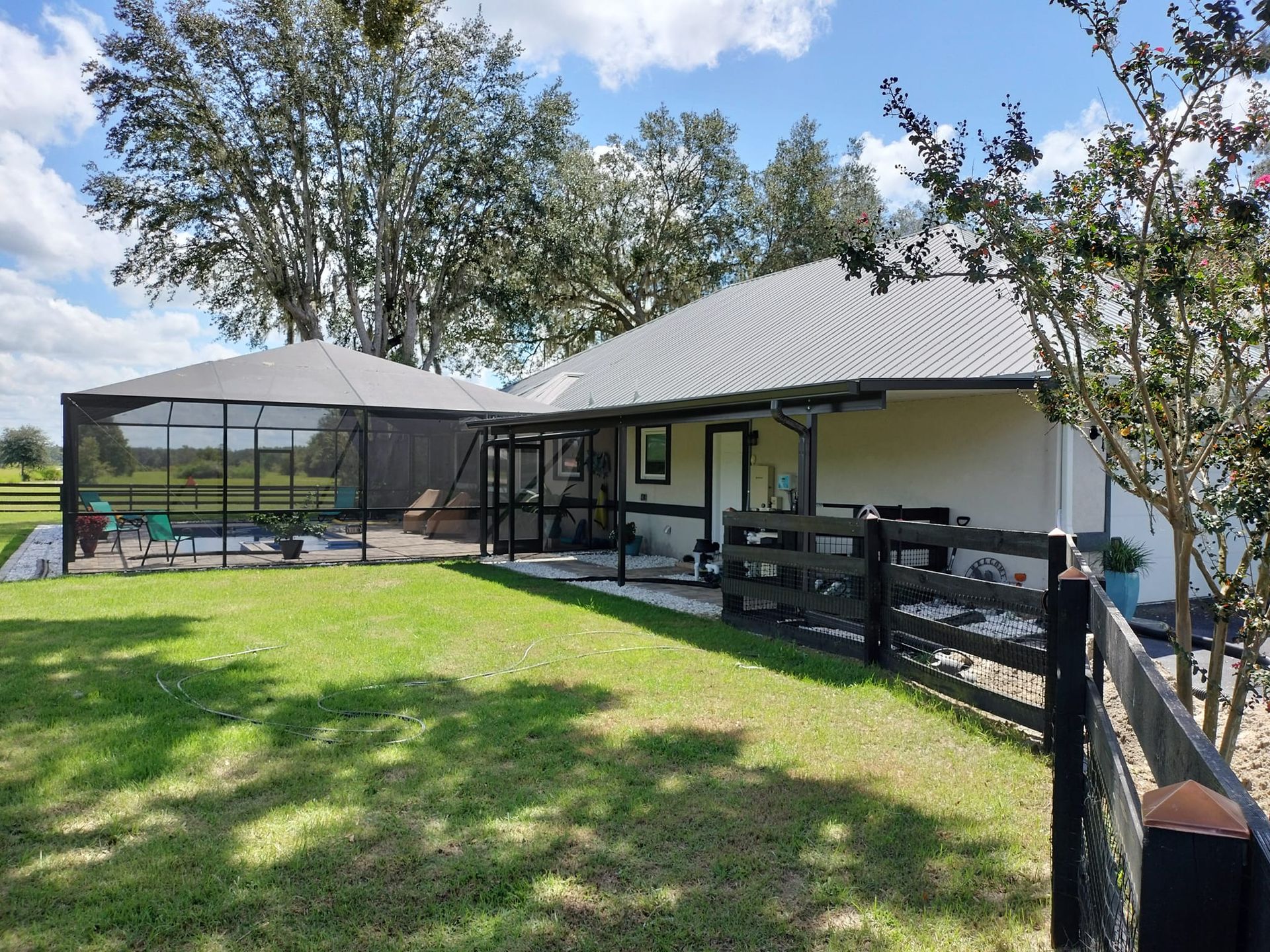 A house with a screened in porch and a fence in front of it.