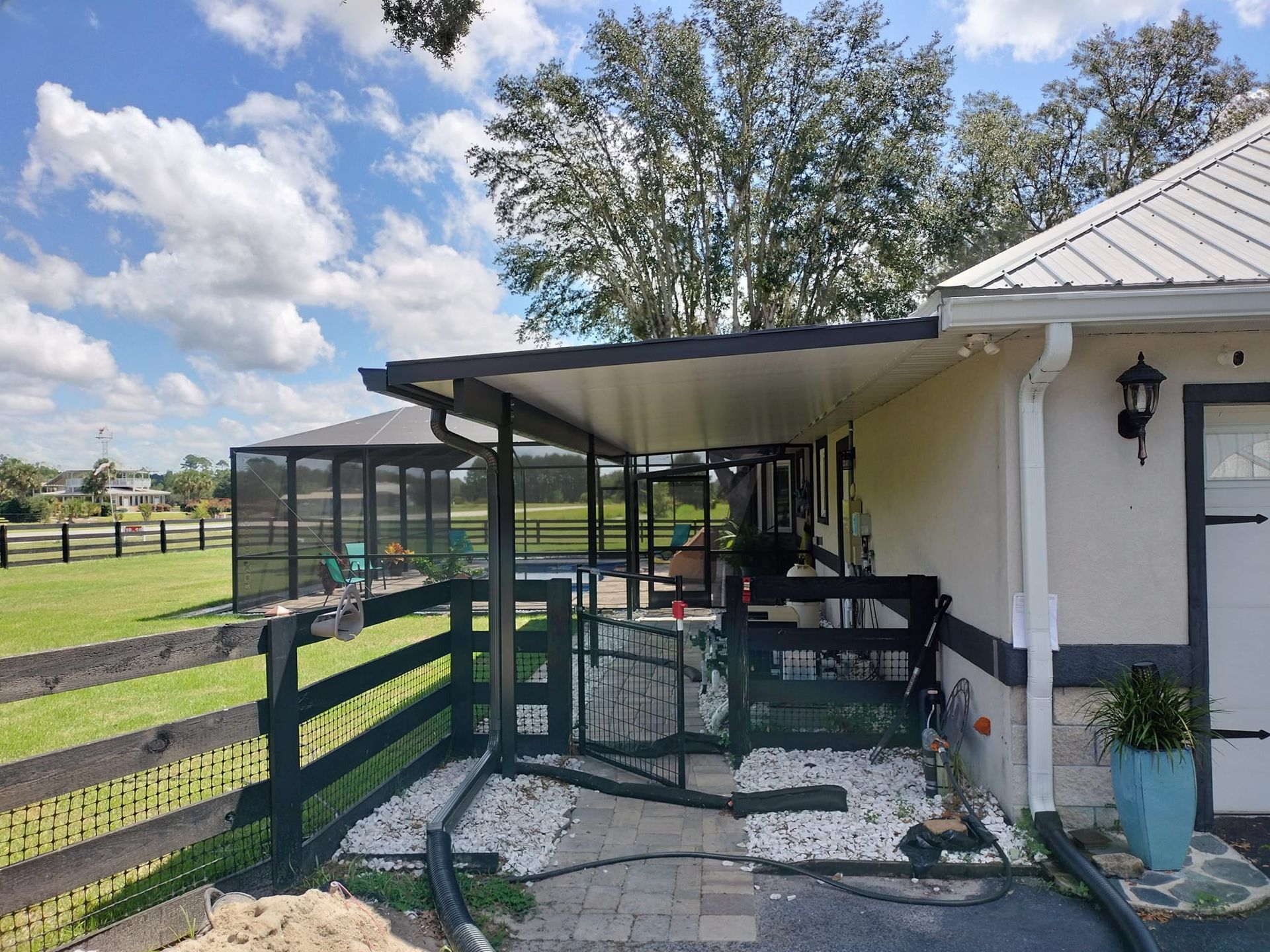 A house with a covered porch and a fence in front of it.