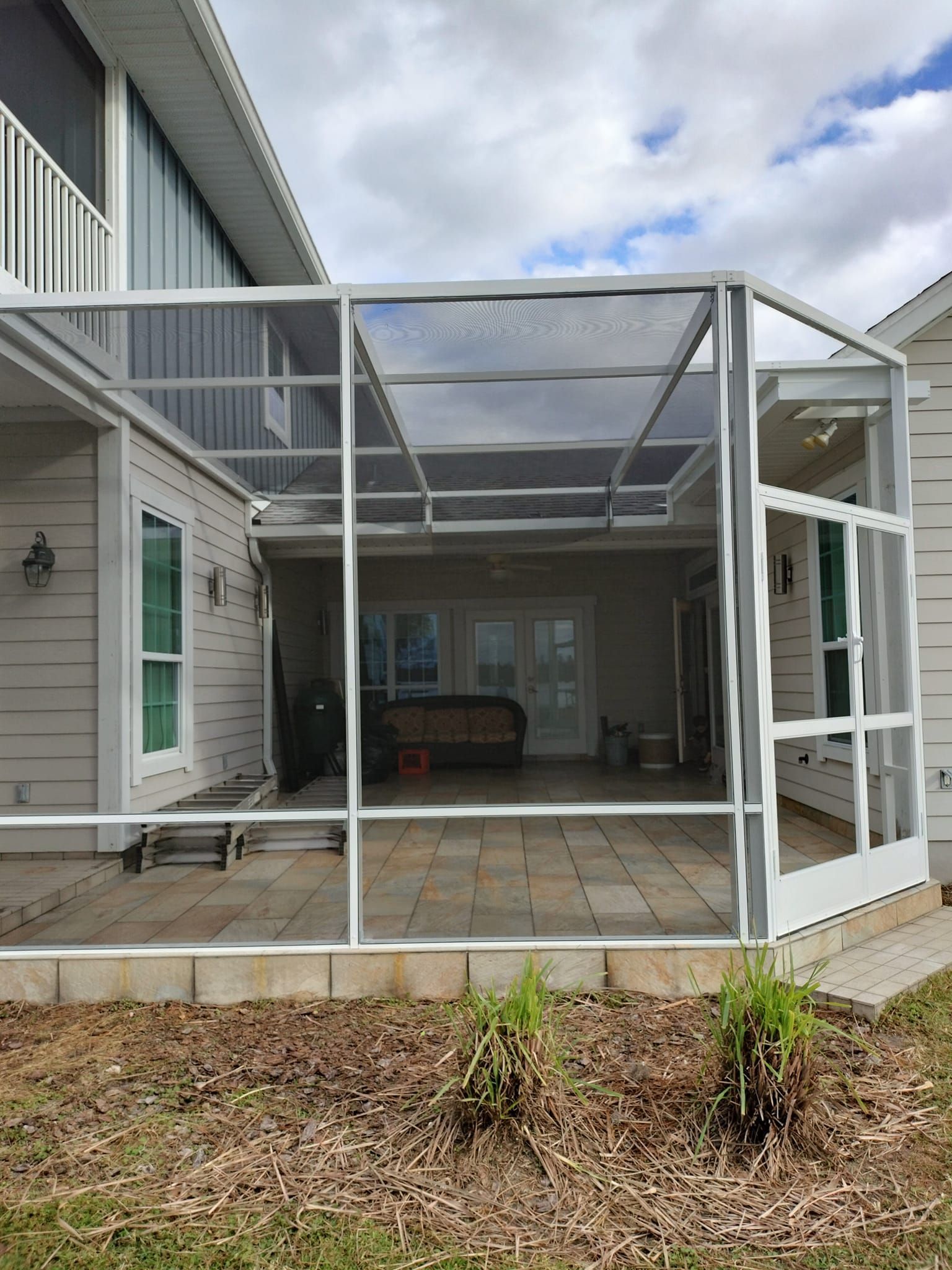 A screened in porch with a patio in the backyard of a house.