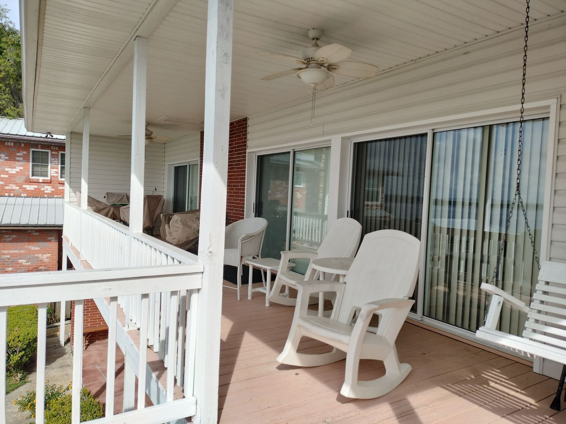 There are two rocking chairs on the porch of a house.