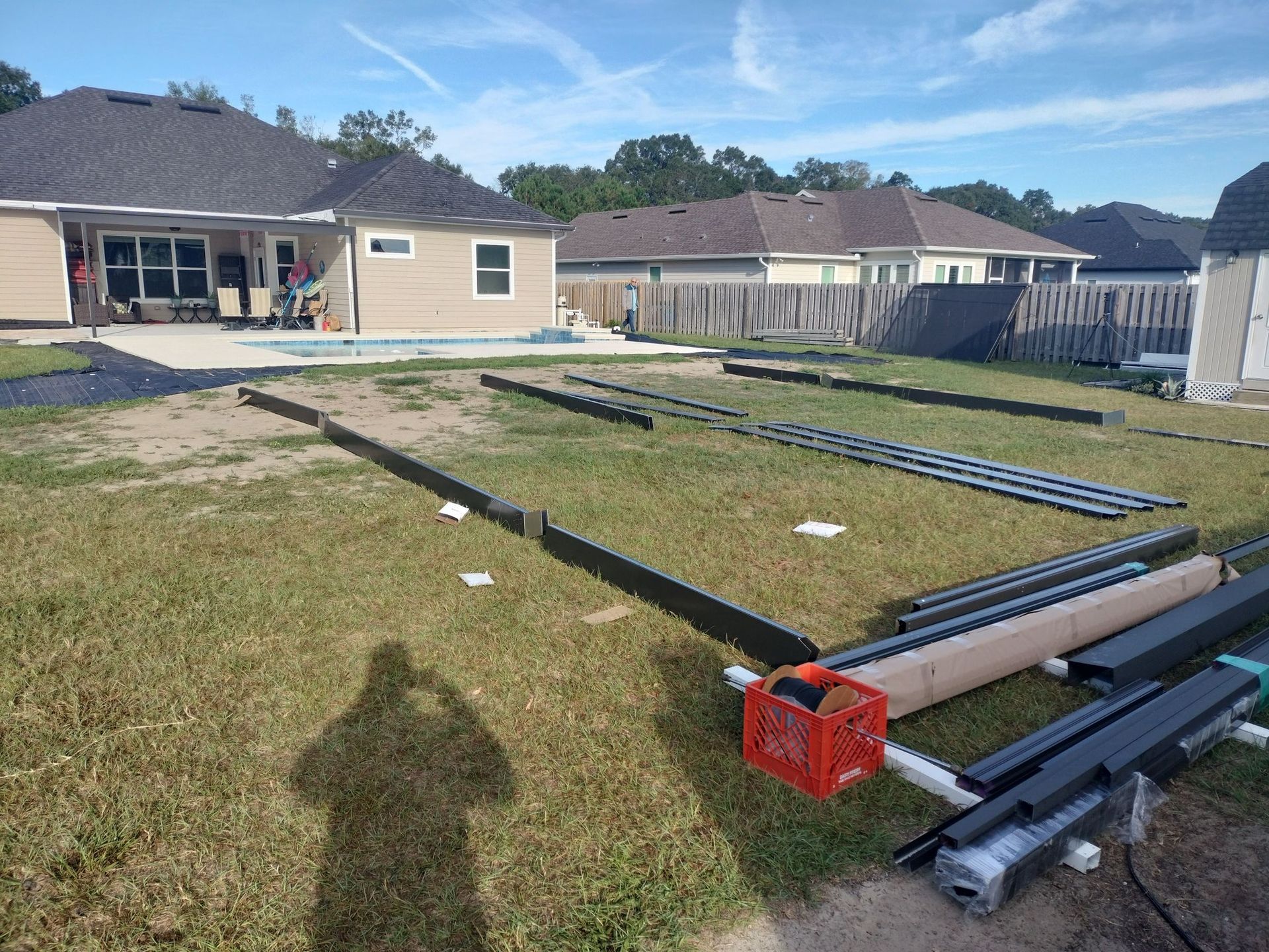 A shadow of a person is cast on the grass in front of a house.
