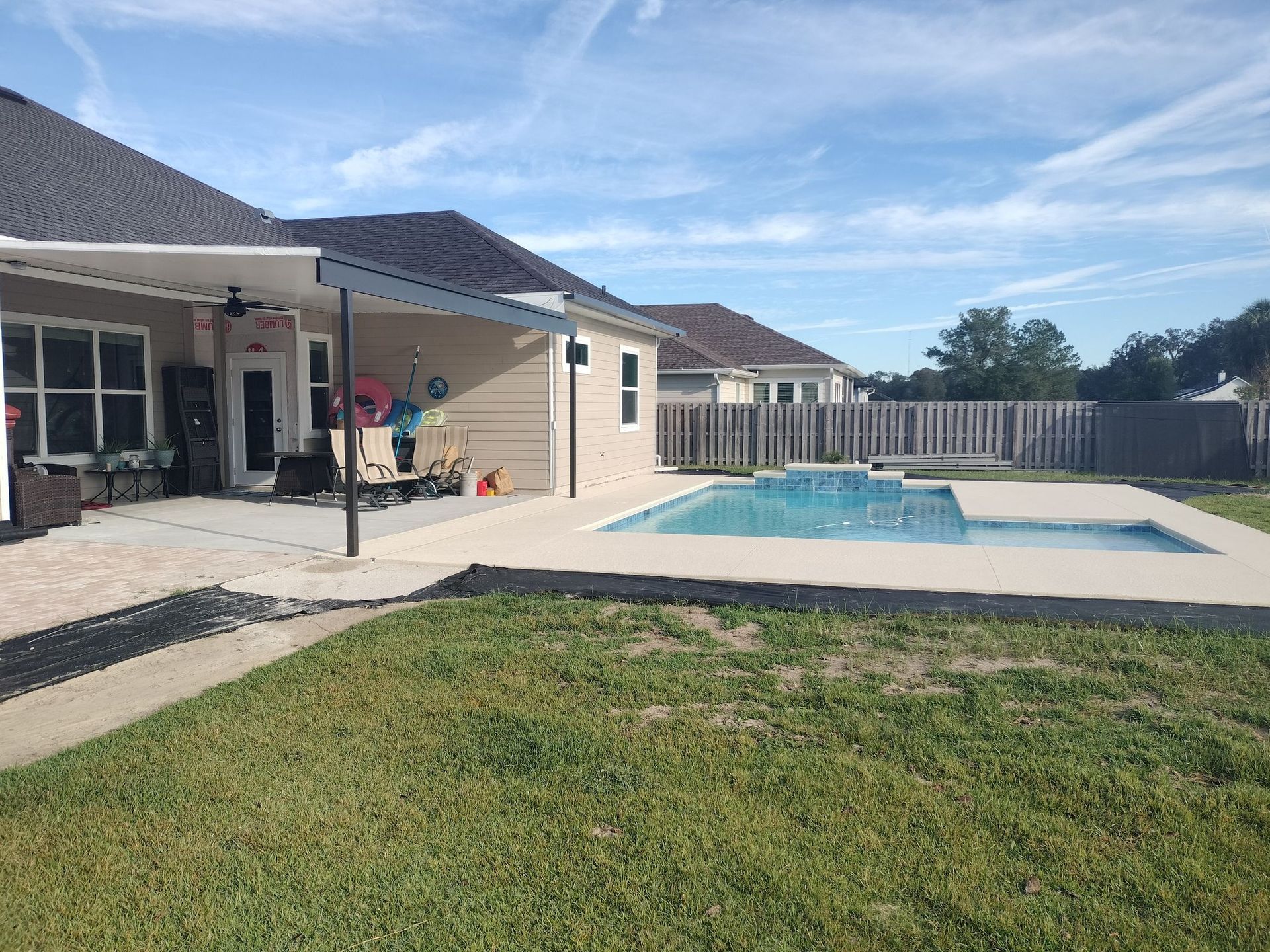 There is a large swimming pool in the backyard of a house.