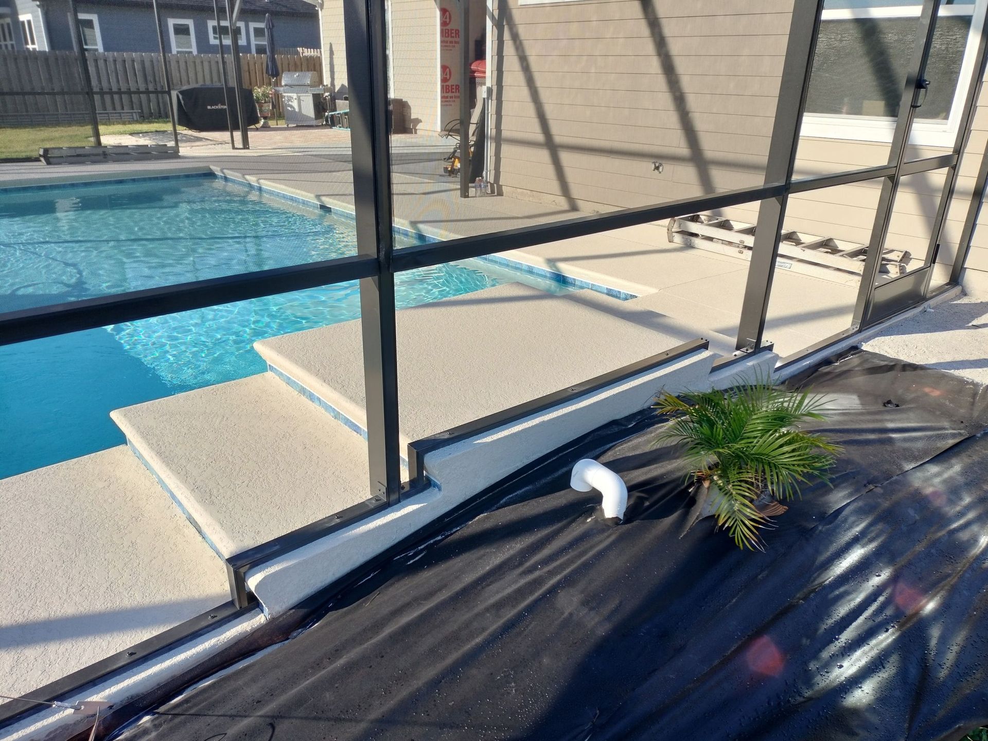 A swimming pool is behind a screened in area