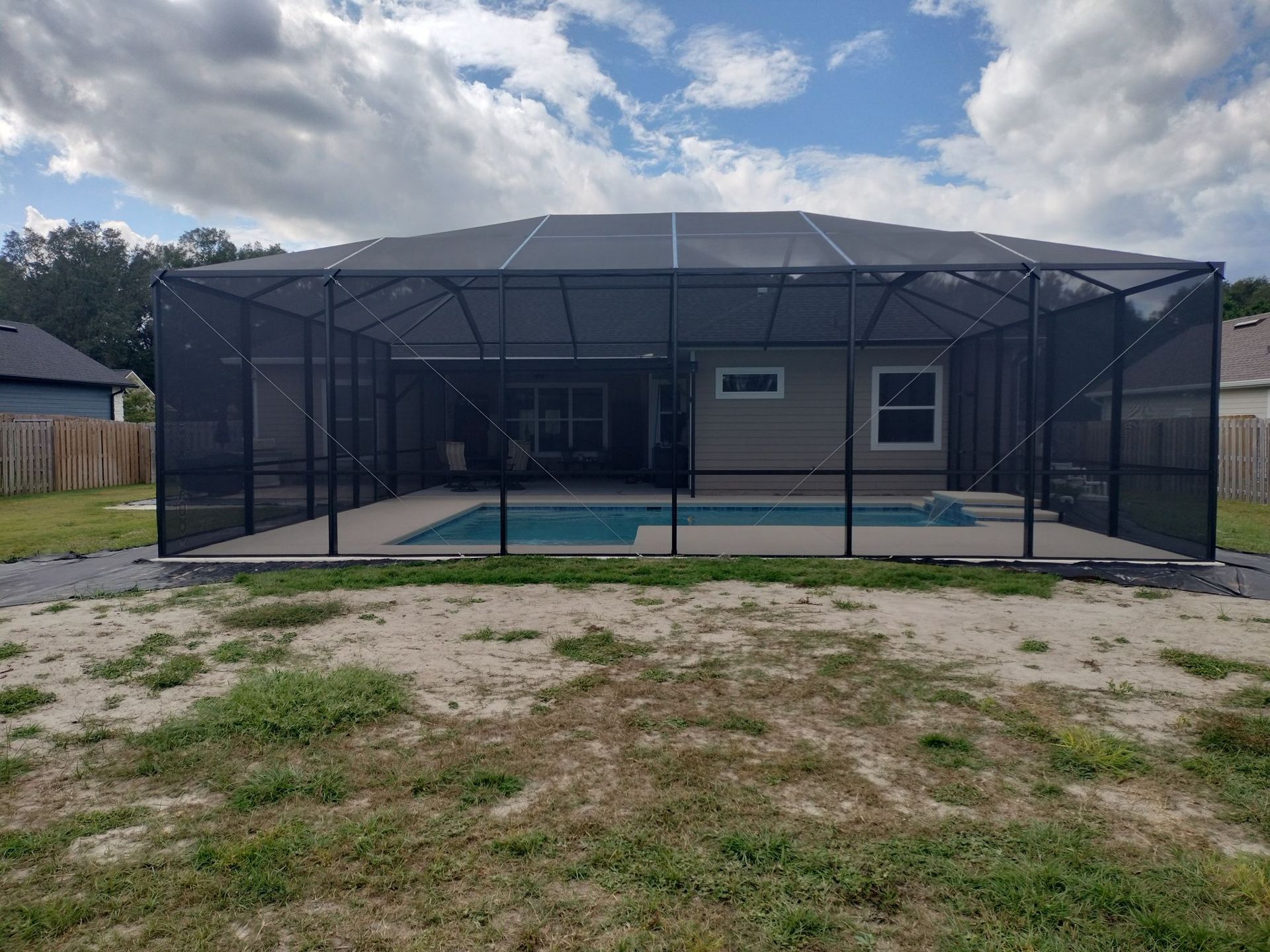The backyard of a house with a pool and a screened in area.